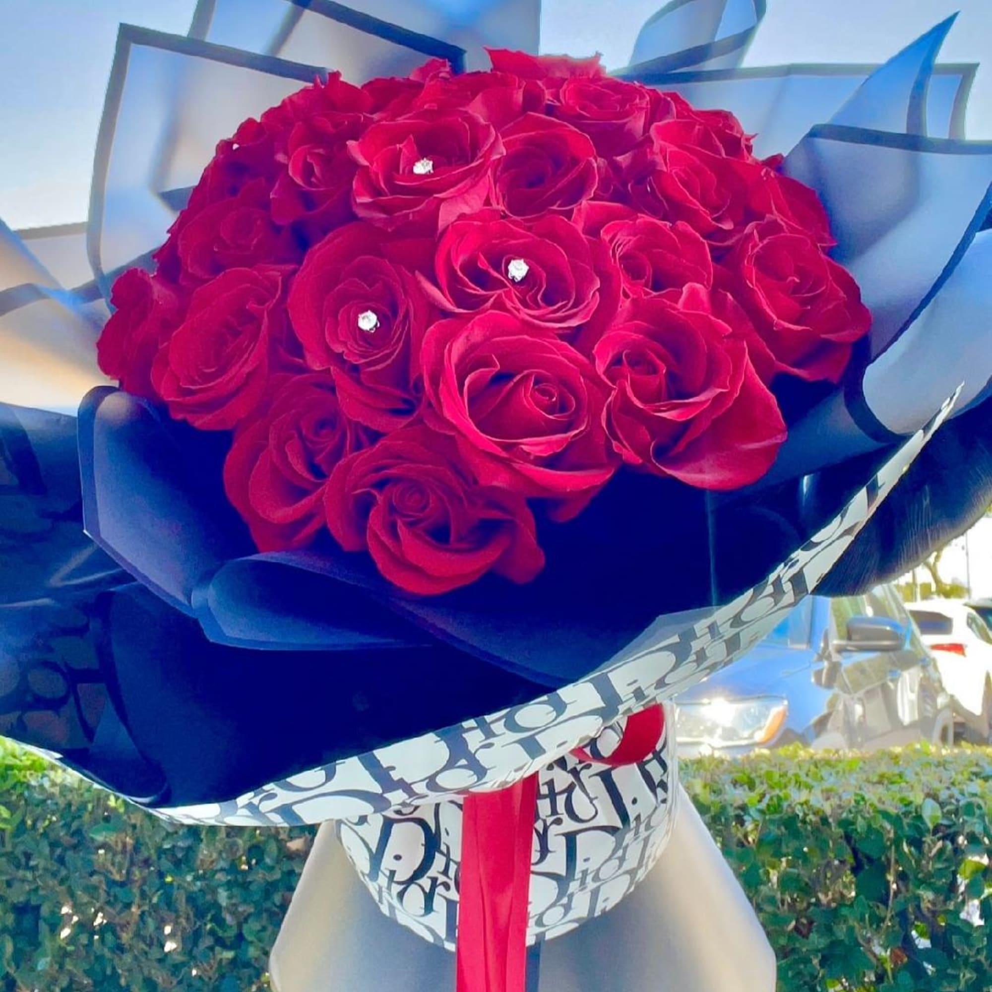 Bouquet of red roses wrapped in blue and white paper with a red ribbon