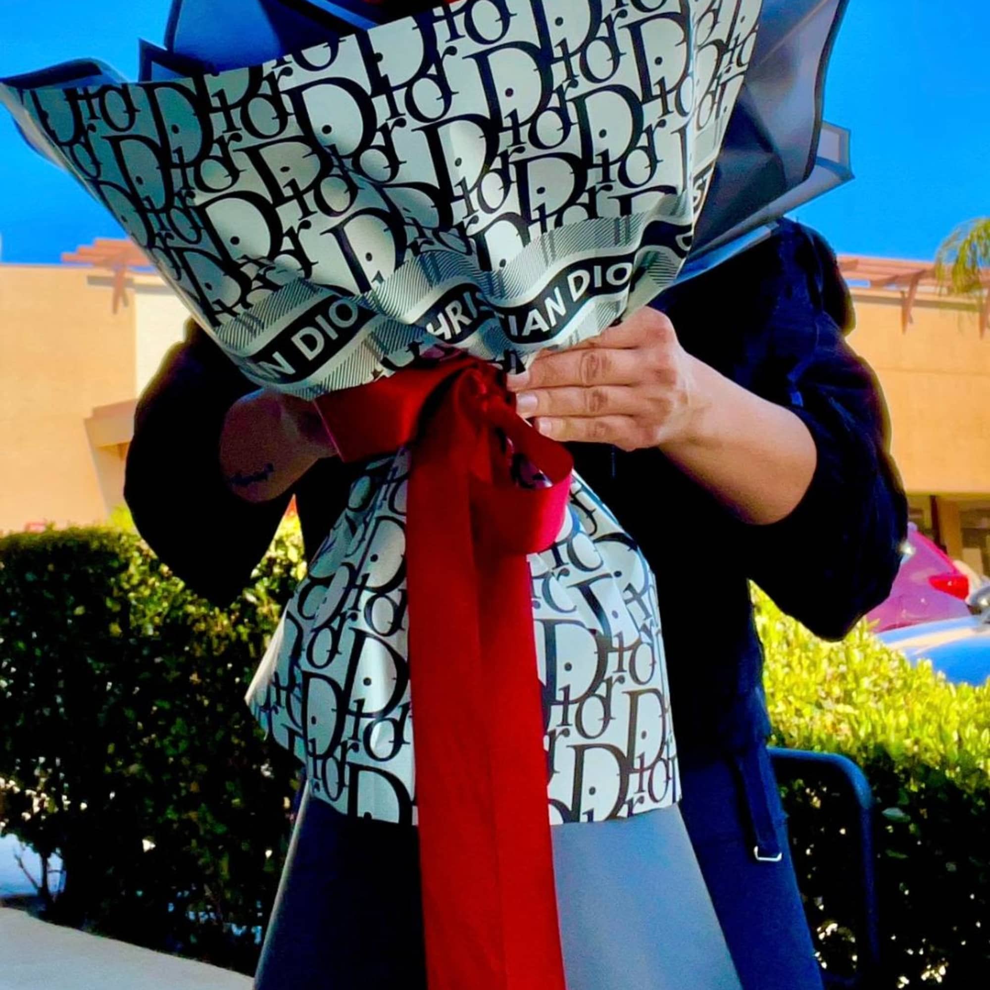 Person holding a large wrapped bouquet with red flowers