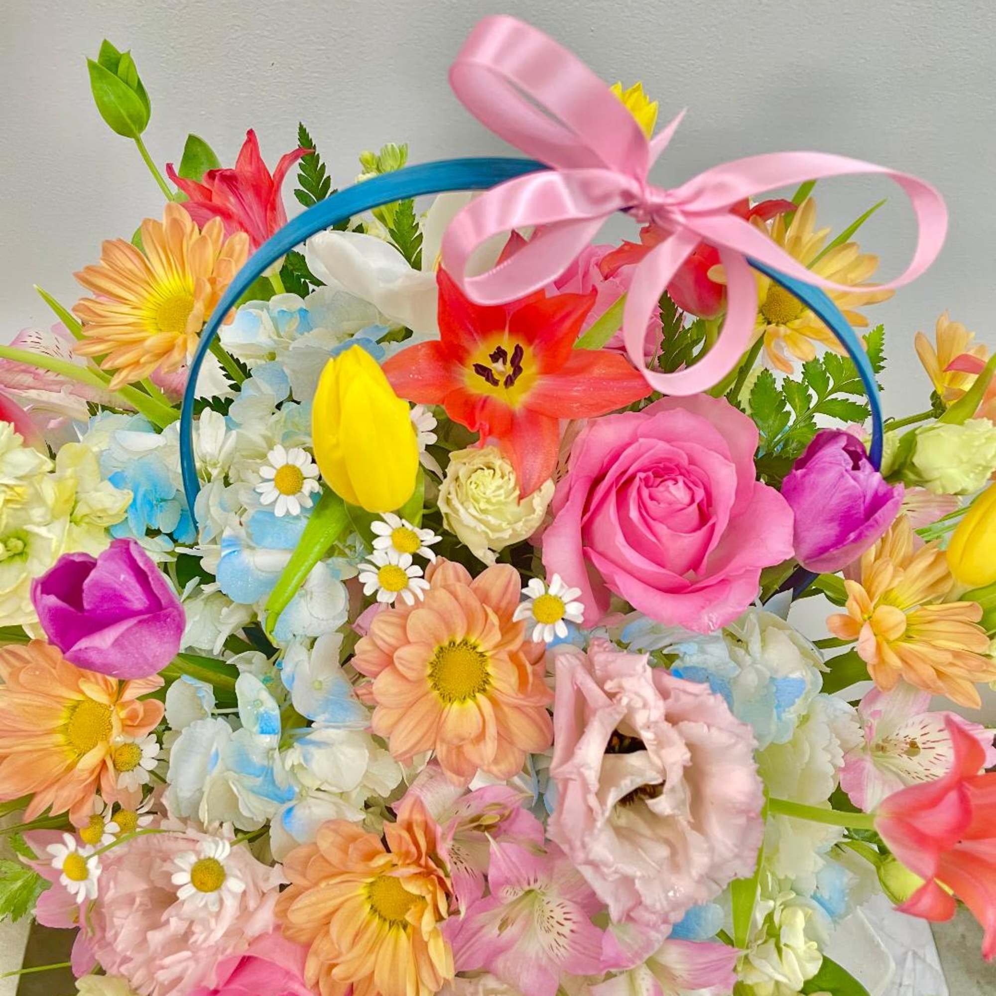 Colorful mixed flower basket with a pink ribbon bow
