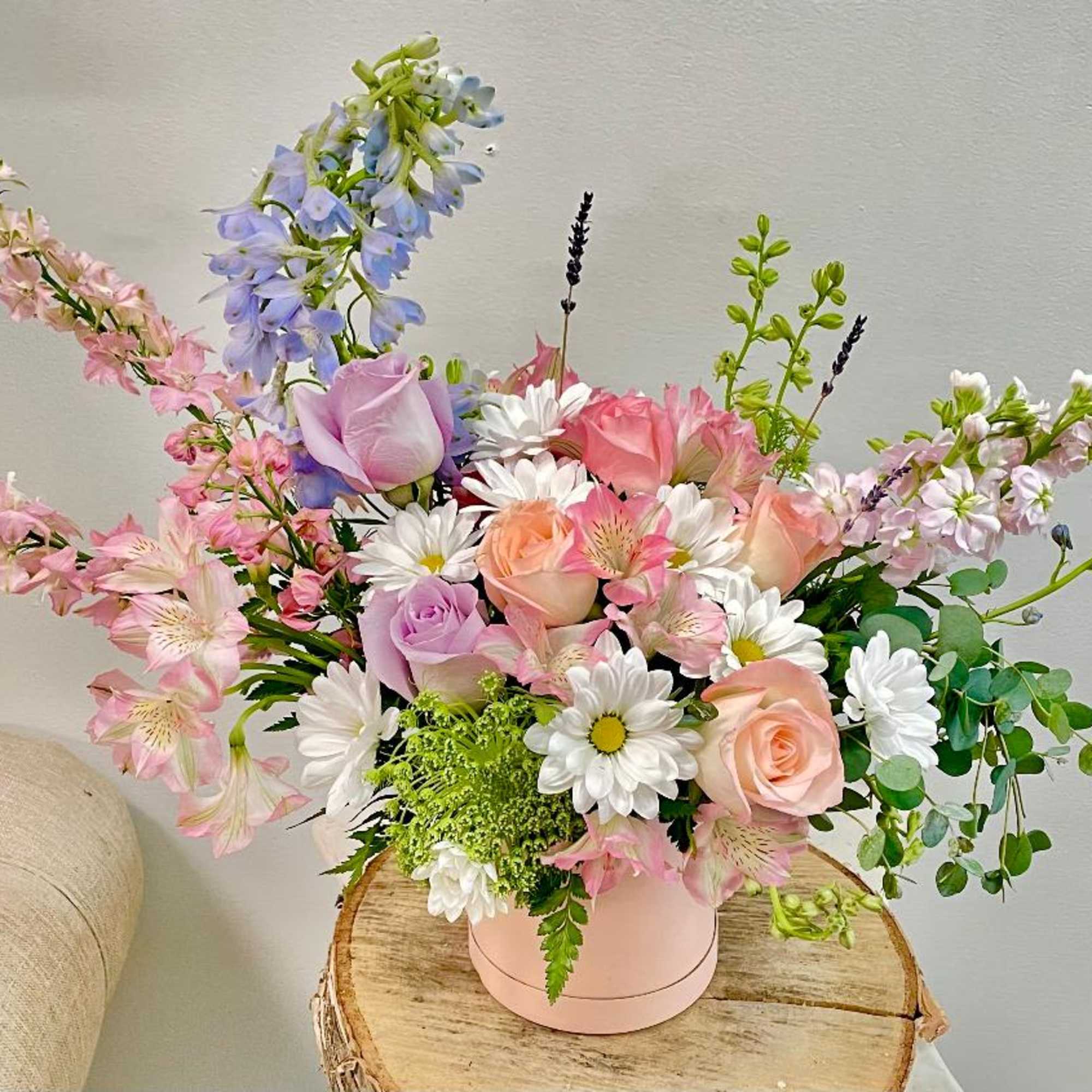 Pastel bouquet of roses, daisies, and mixed blooms in a pink box