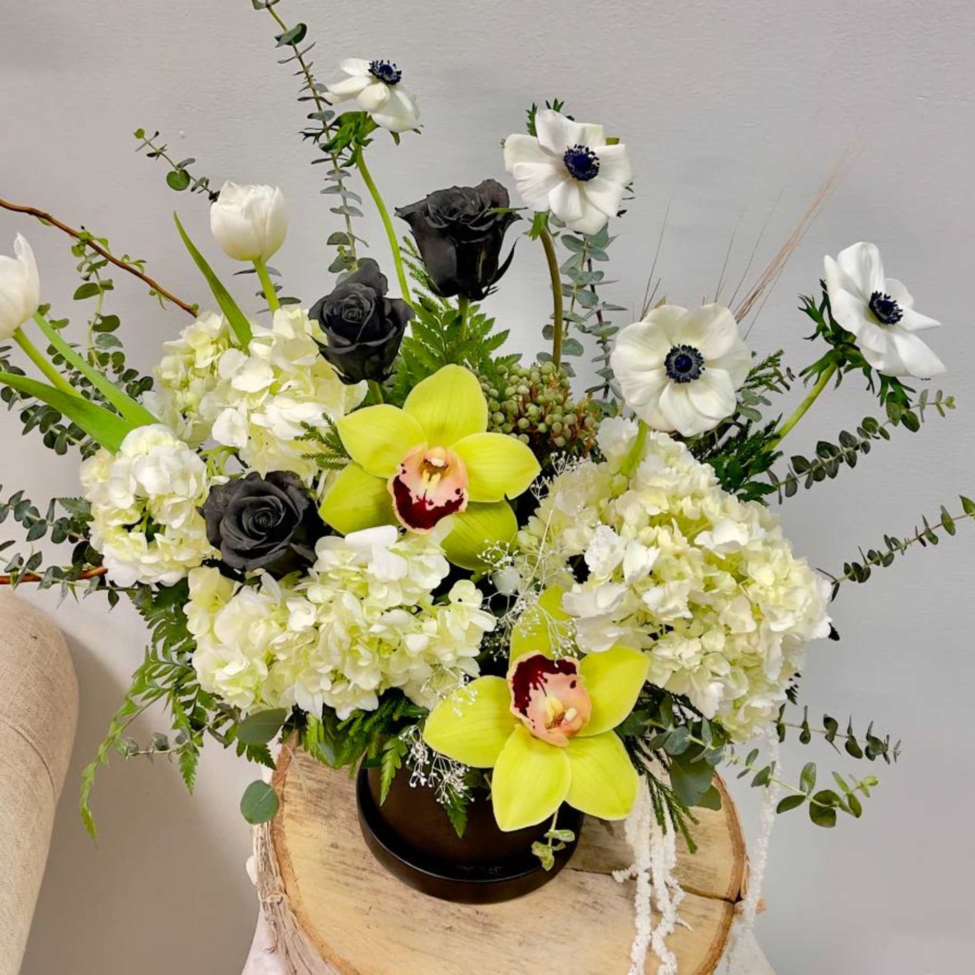 Arrangement of white tulips, orchids, hydrangeas, and black roses in a vase