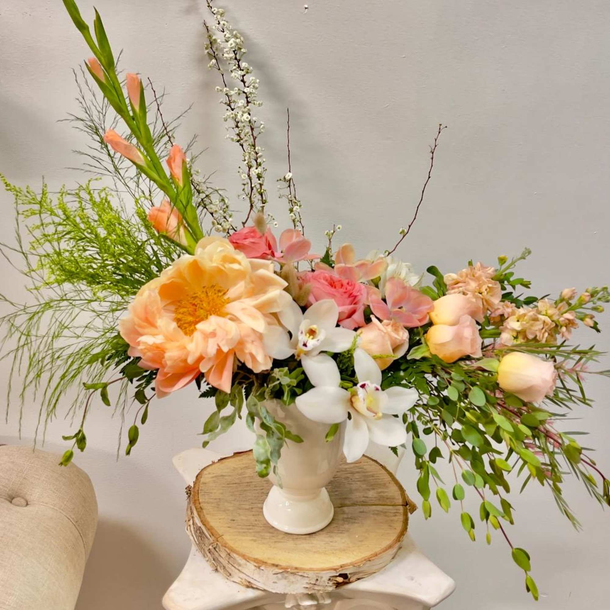Peach and white floral arrangement in a white vase
