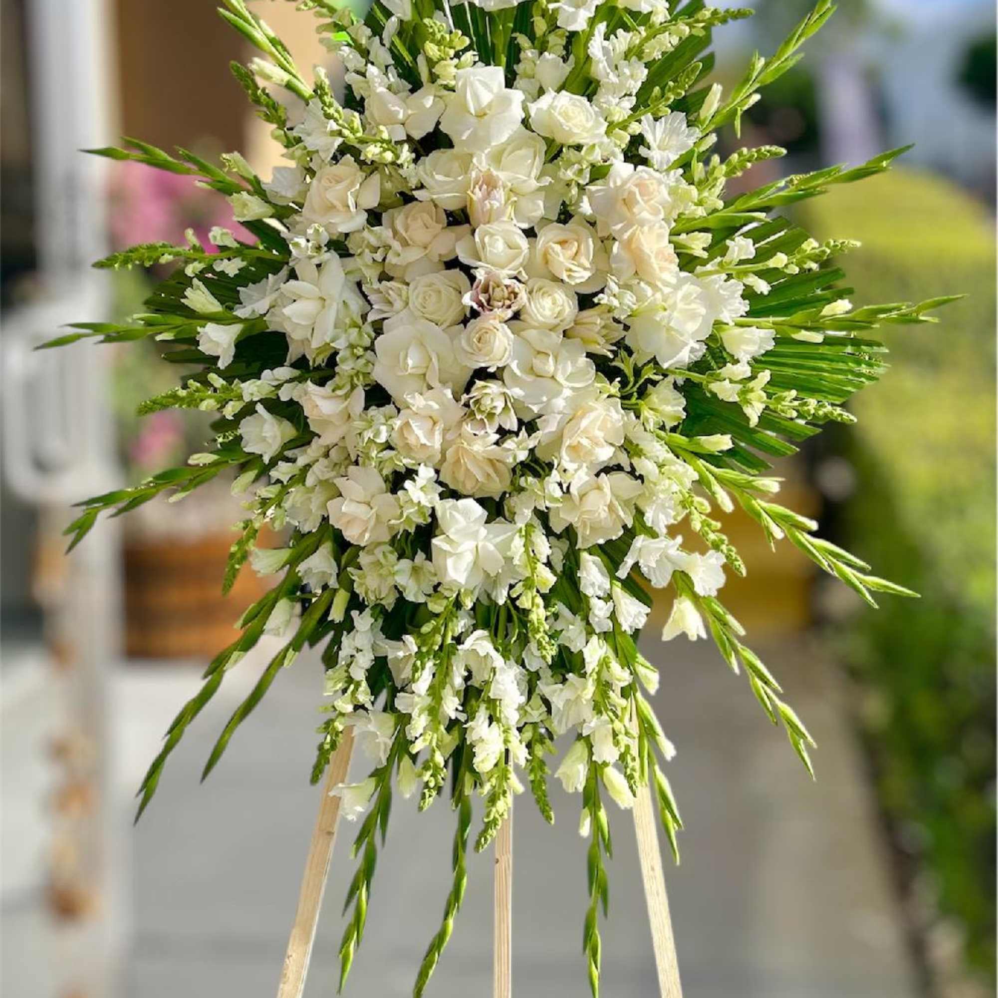 White floral standing spray on an easel with long green accents