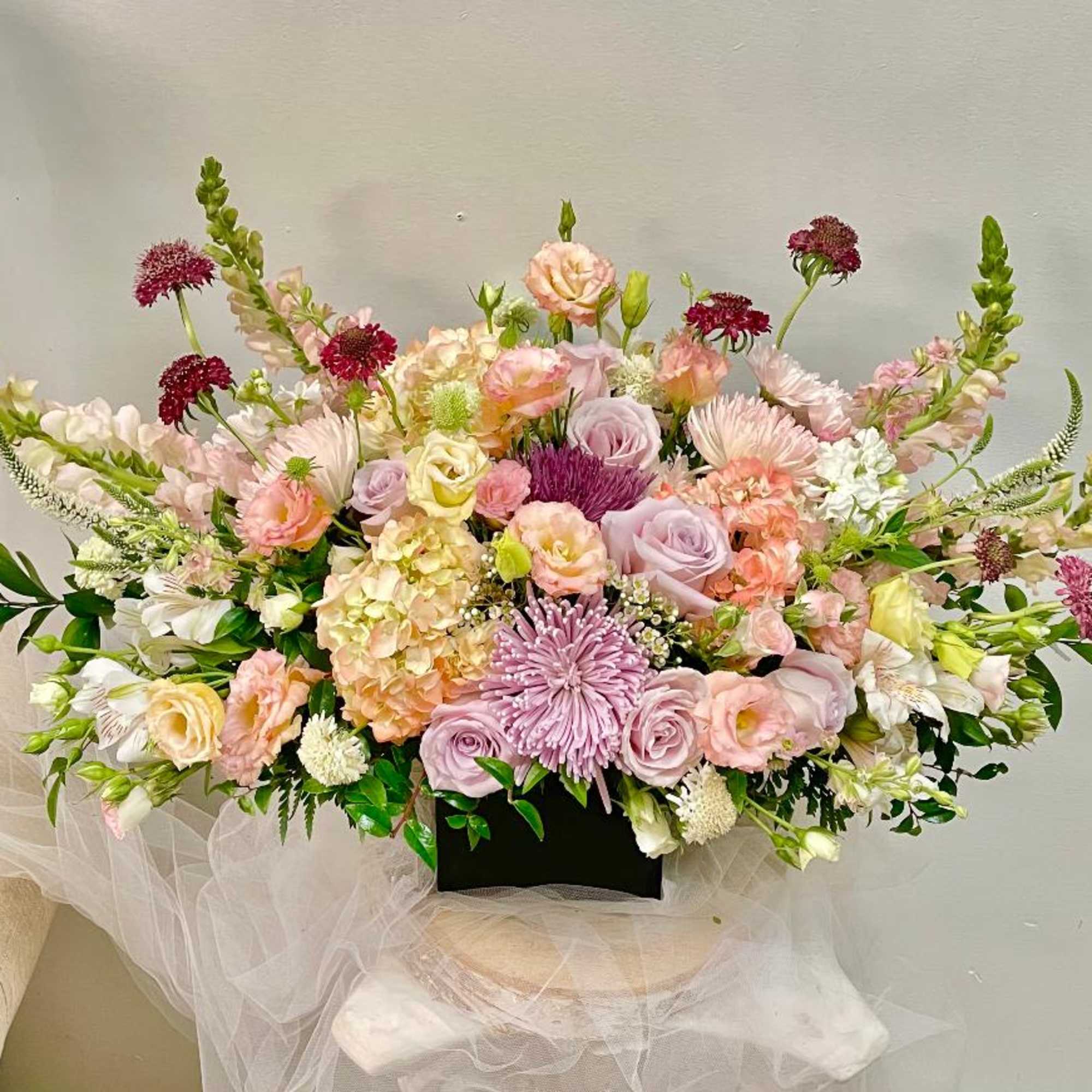 Large pastel floral arrangement in a black container