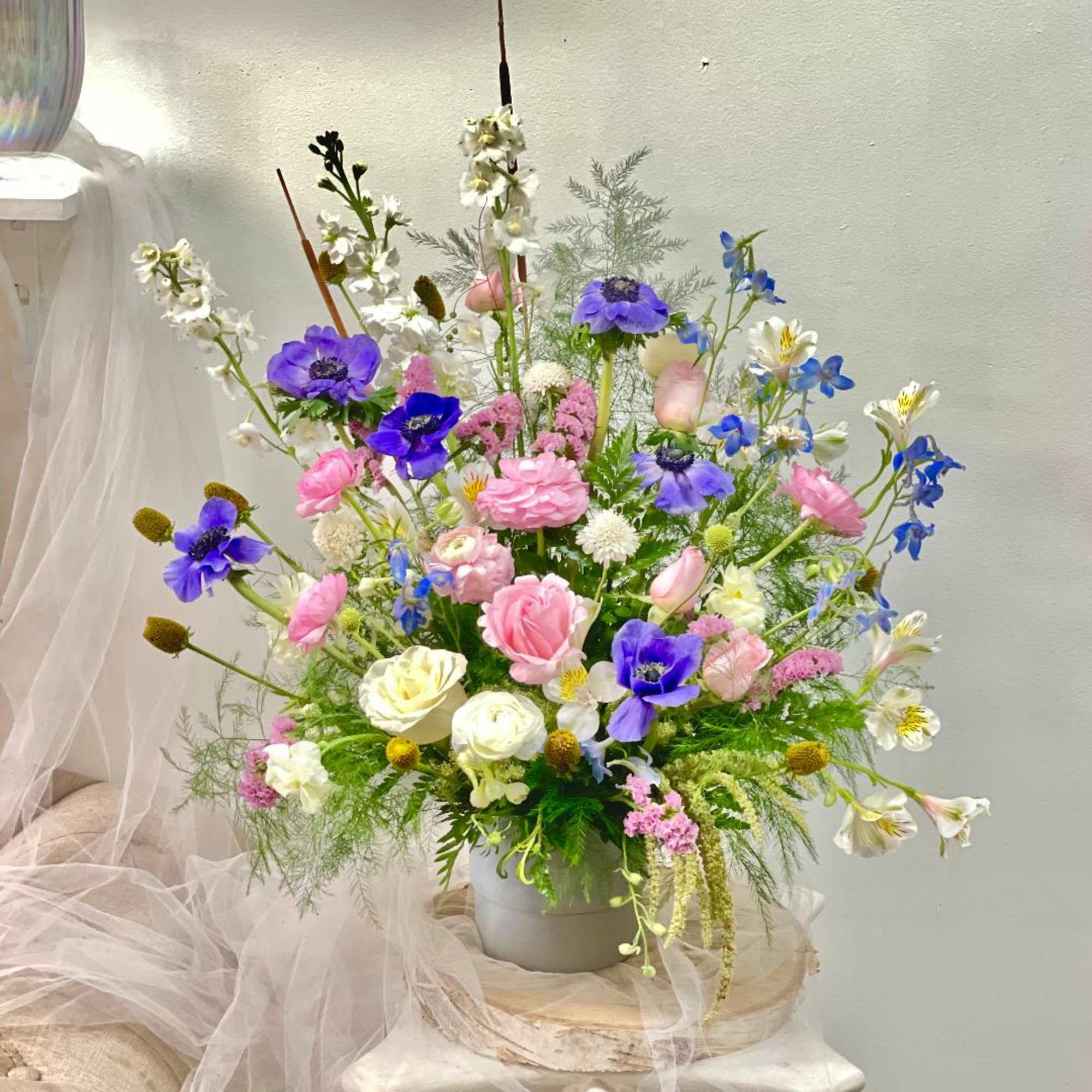 Tall mixed bouquet of pink, purple, white, and blue flowers in a vase