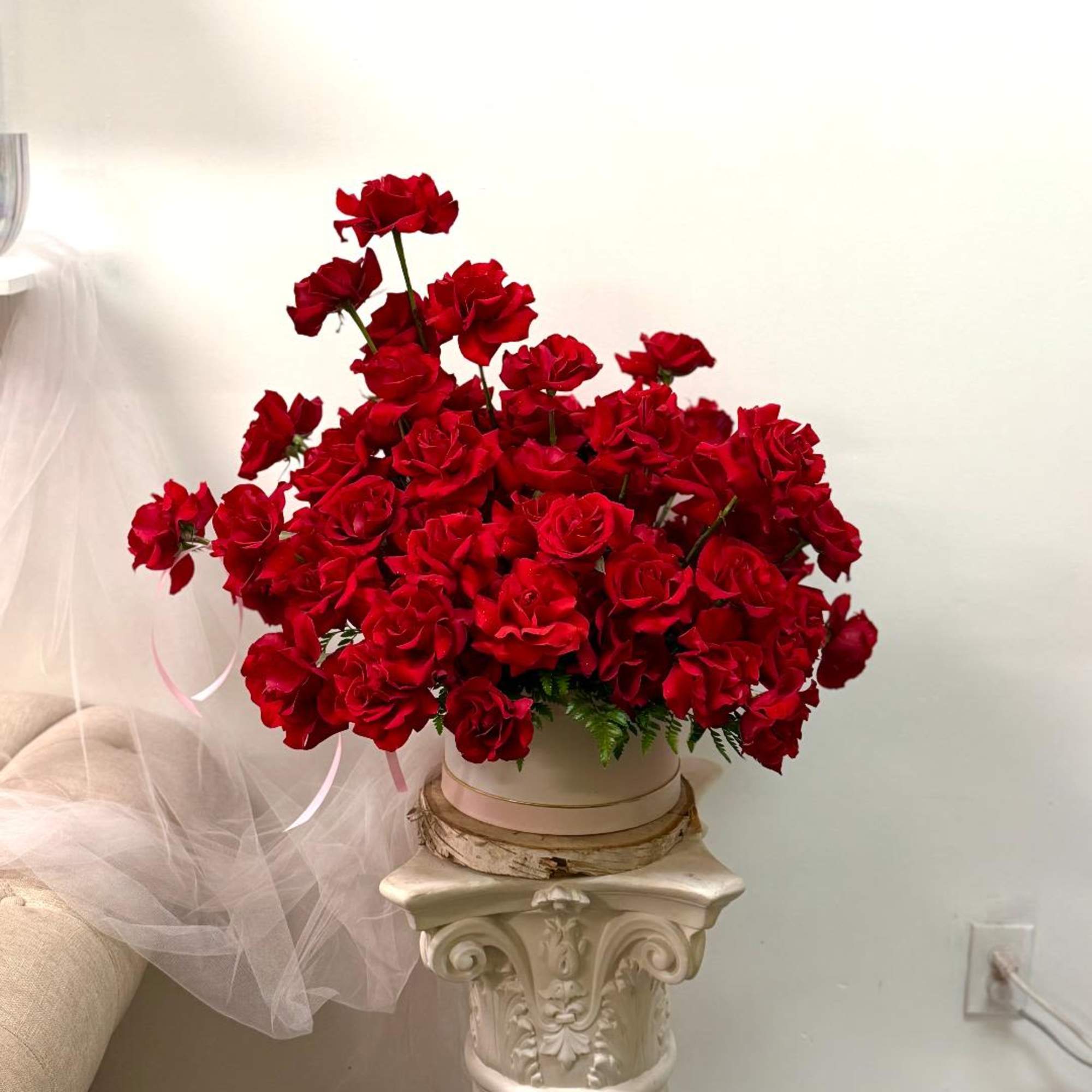 Large bouquet of red roses in a round box on a pedestal