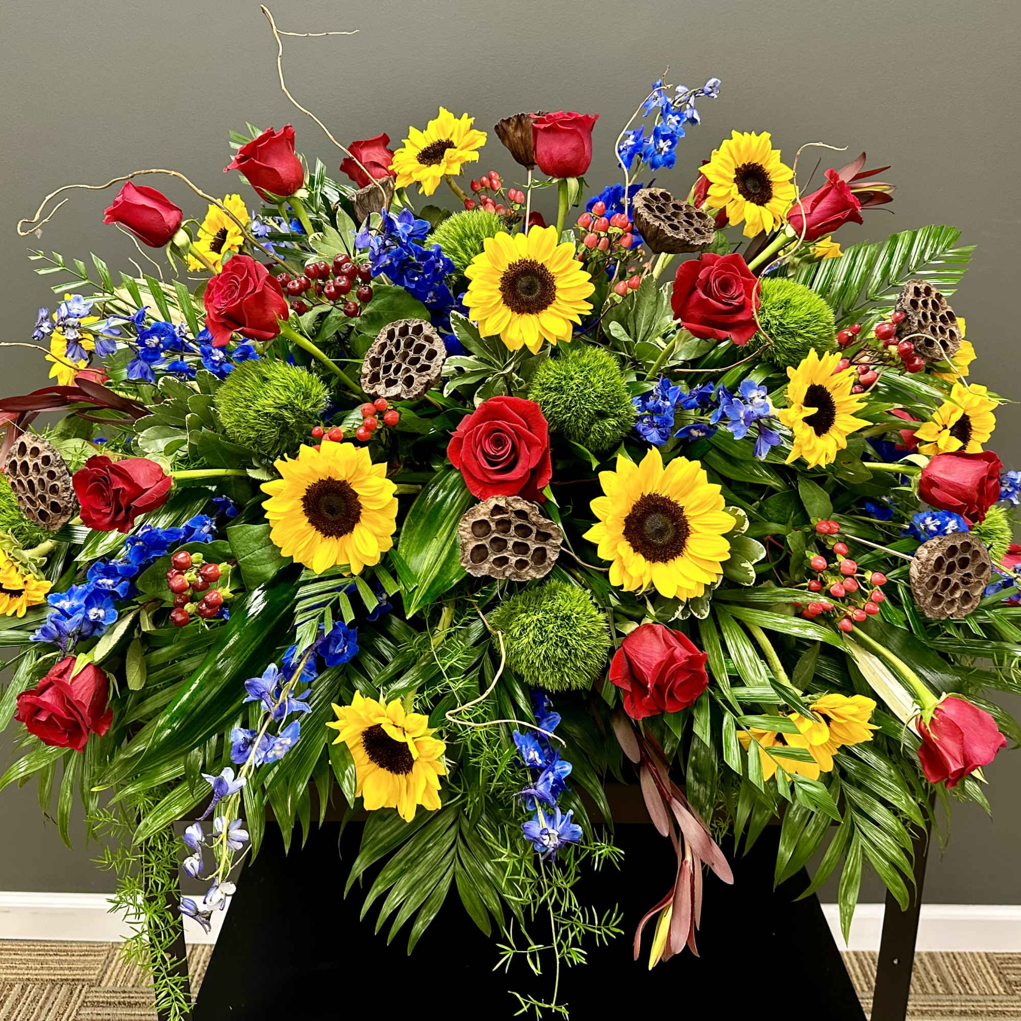 Large arrangement of red roses, sunflowers, and blue flowers