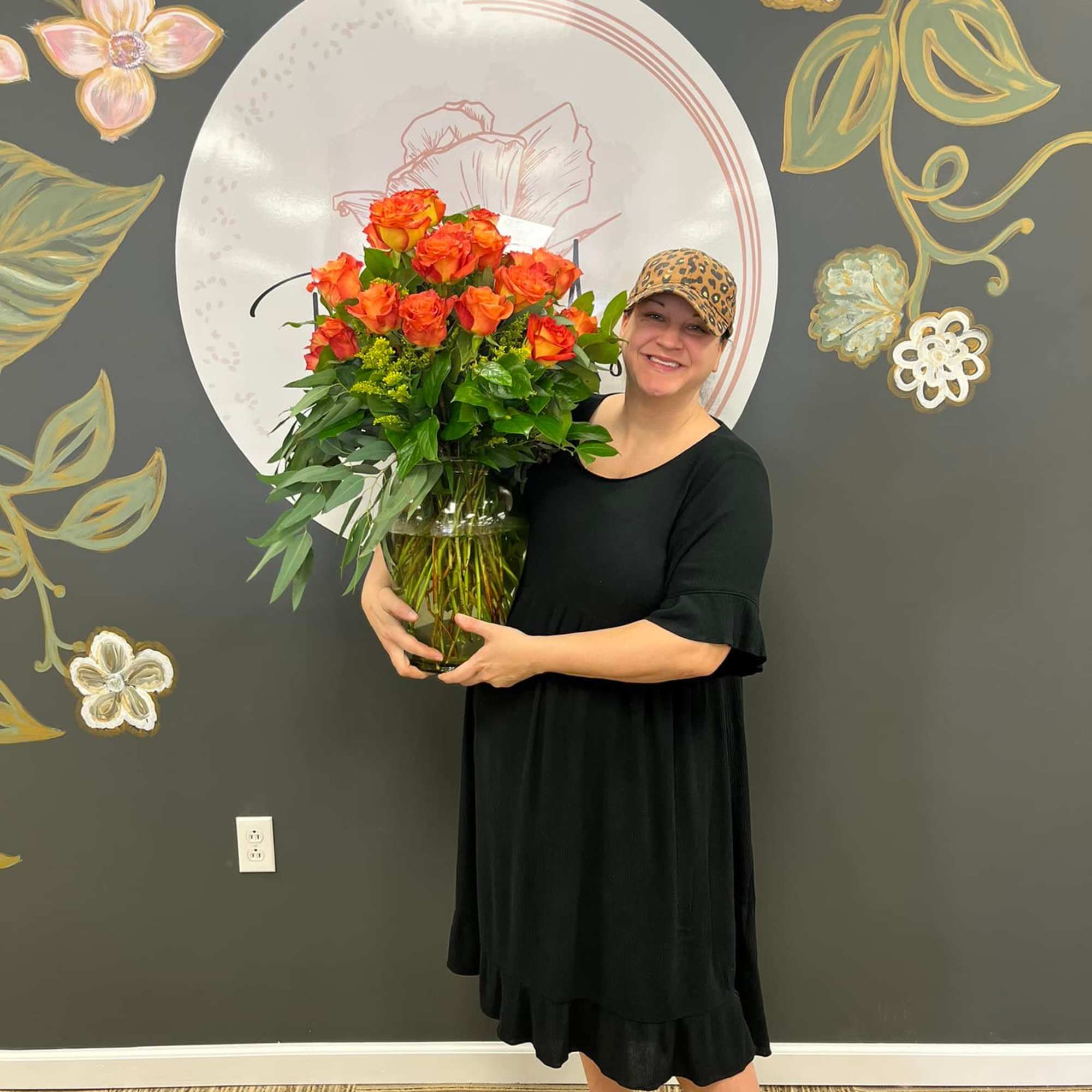 Woman holding a large vase of orange roses