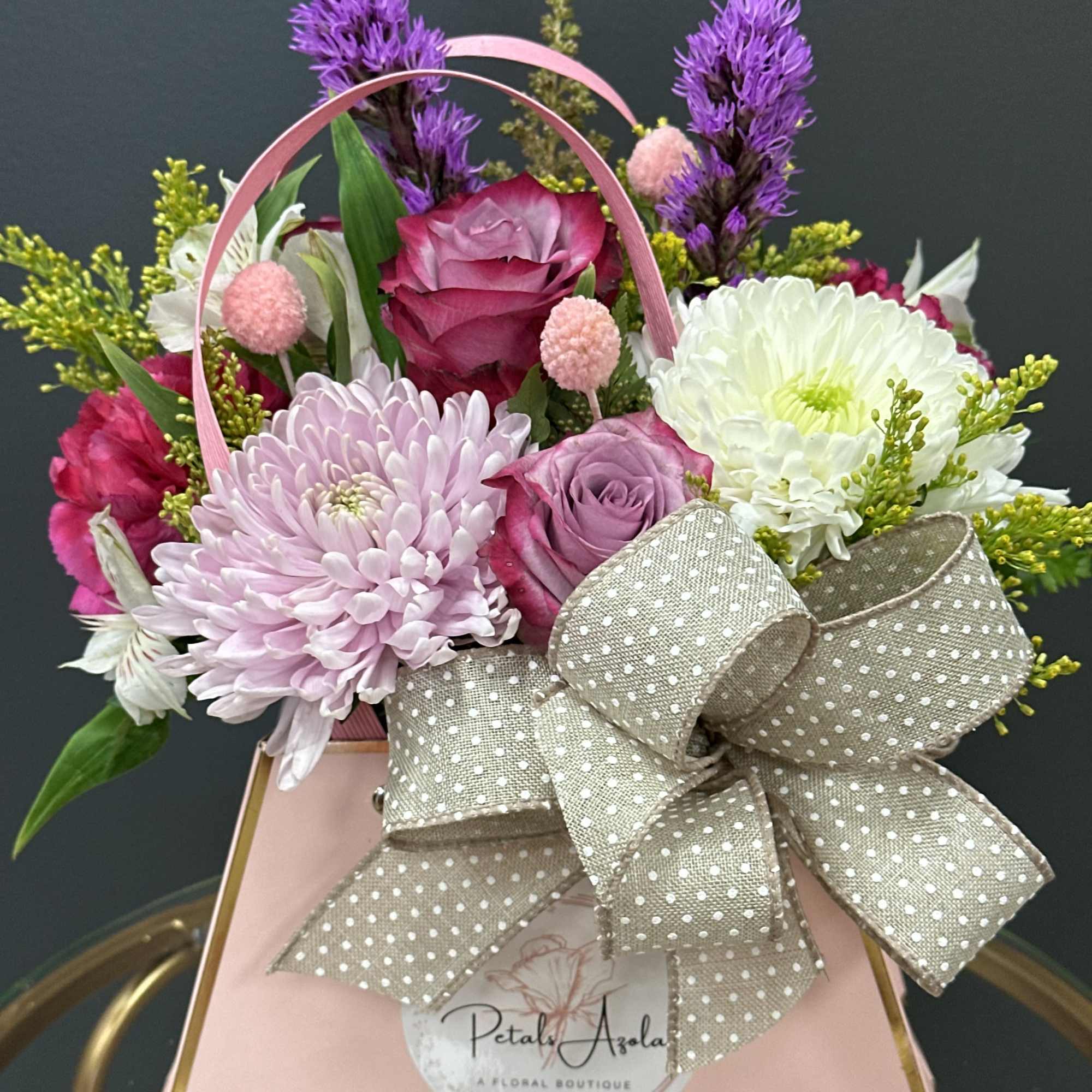 Pink and white flower arrangement in a gift bag with a large bow