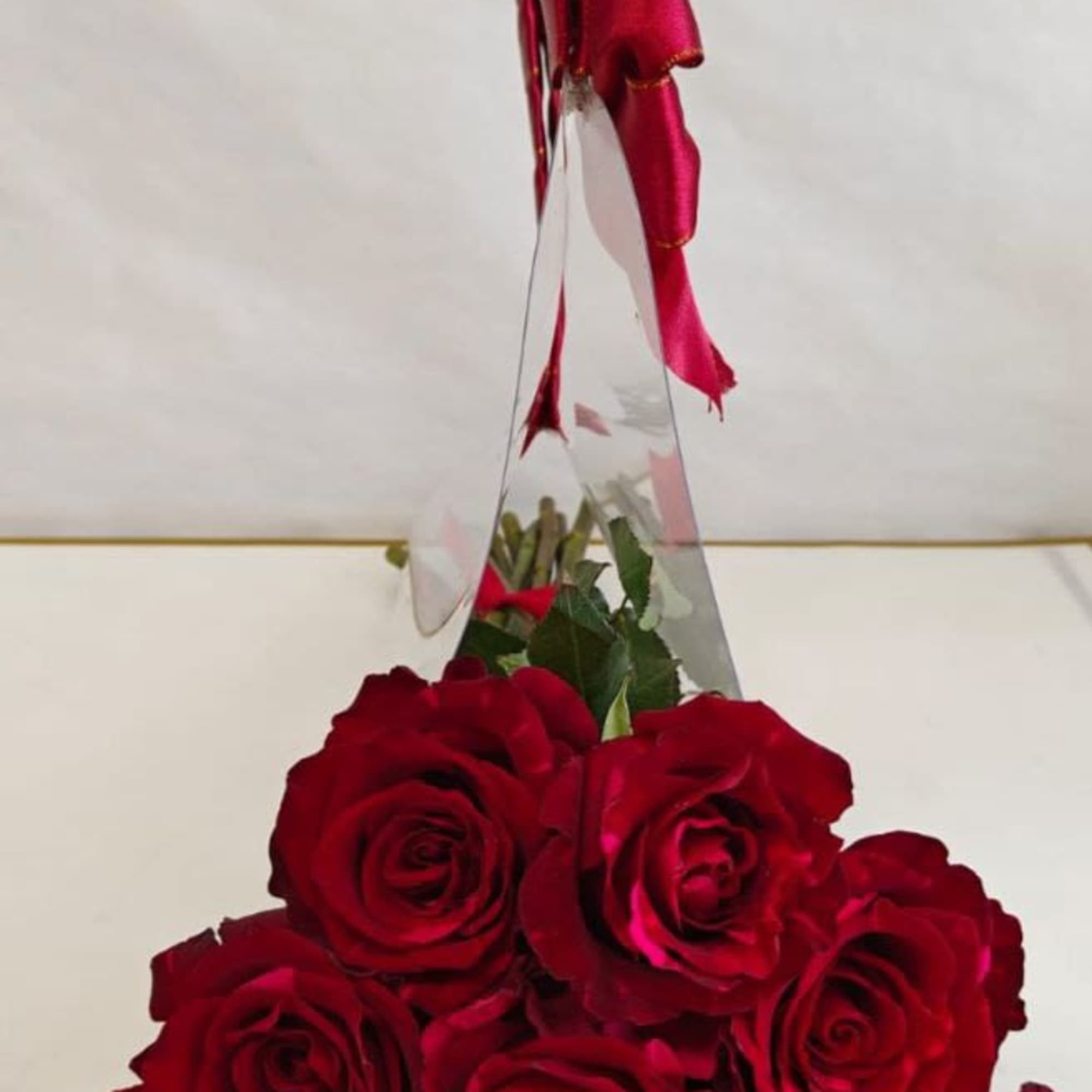 Red rose bouquet wrapped in clear cellophane with a red ribbon