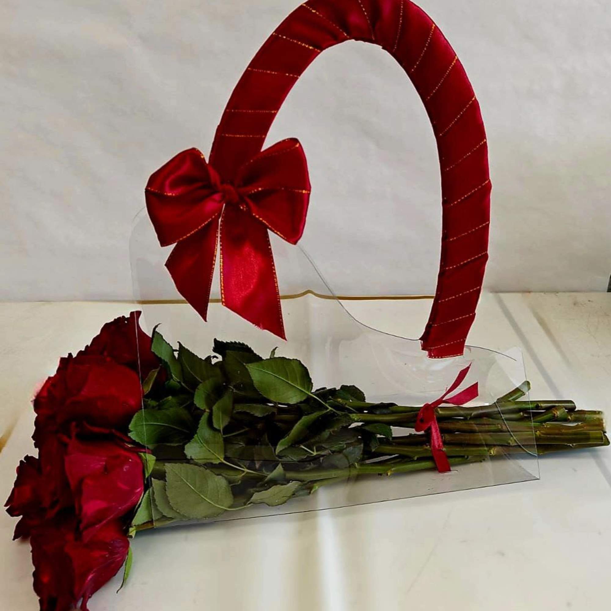 Red roses with a large red ribbon handle and clear wrap