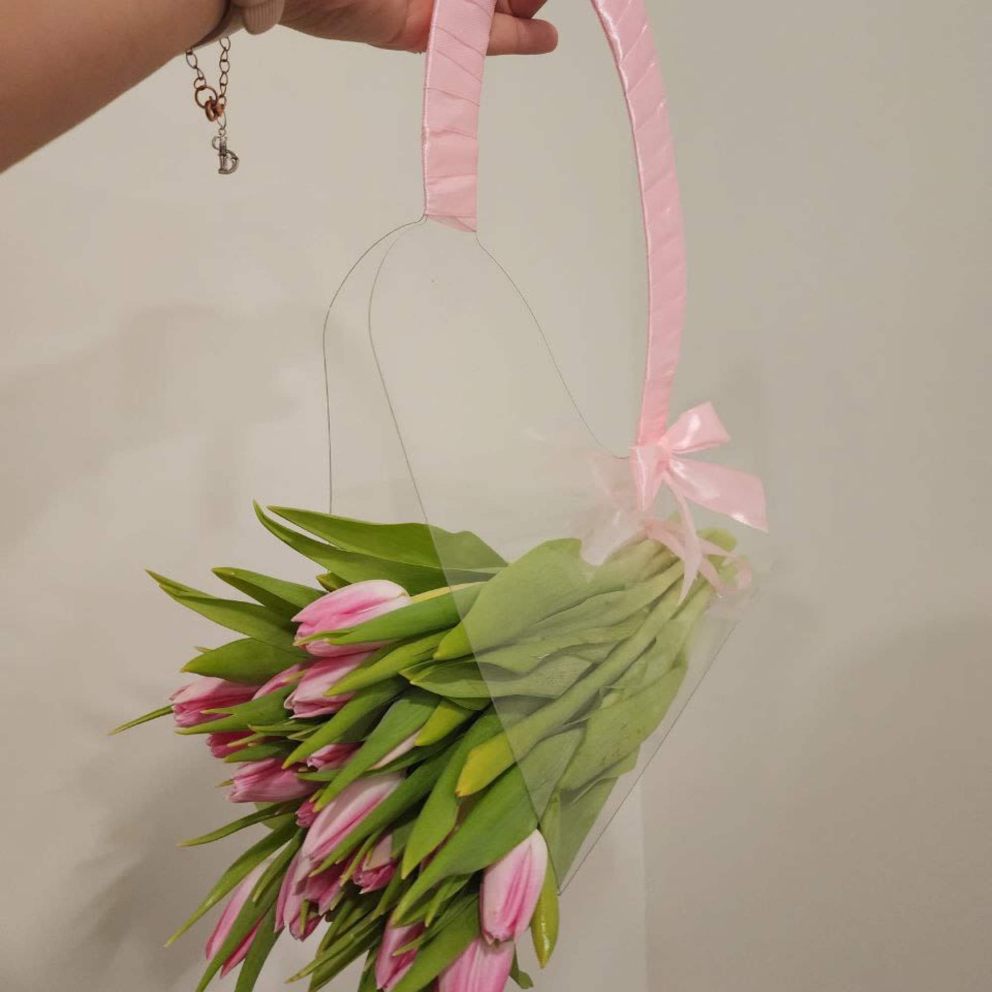 Pink tulips in a clear hanging sleeve with a pink ribbon handle