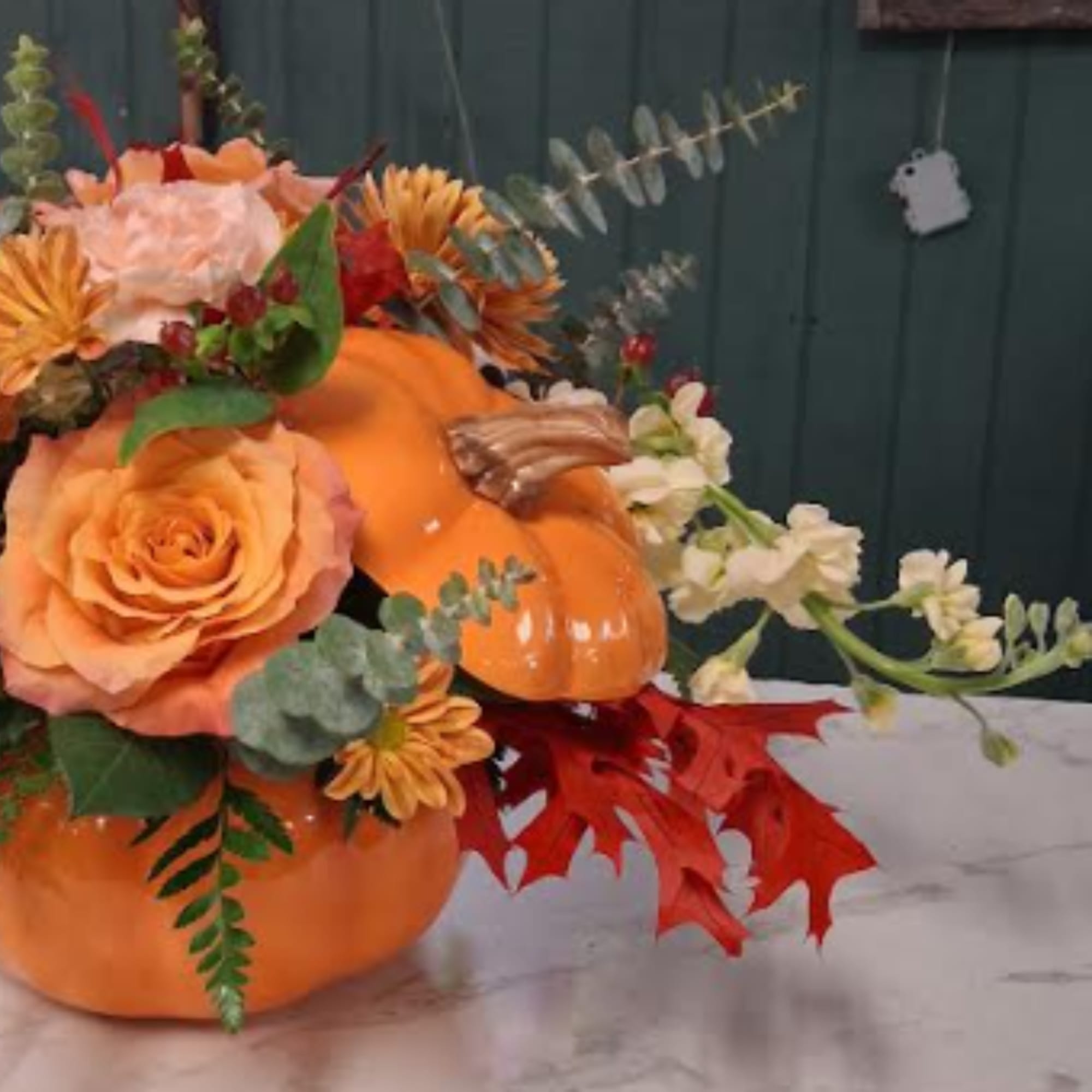 Orange pumpkin arrangement with roses and autumn flowers