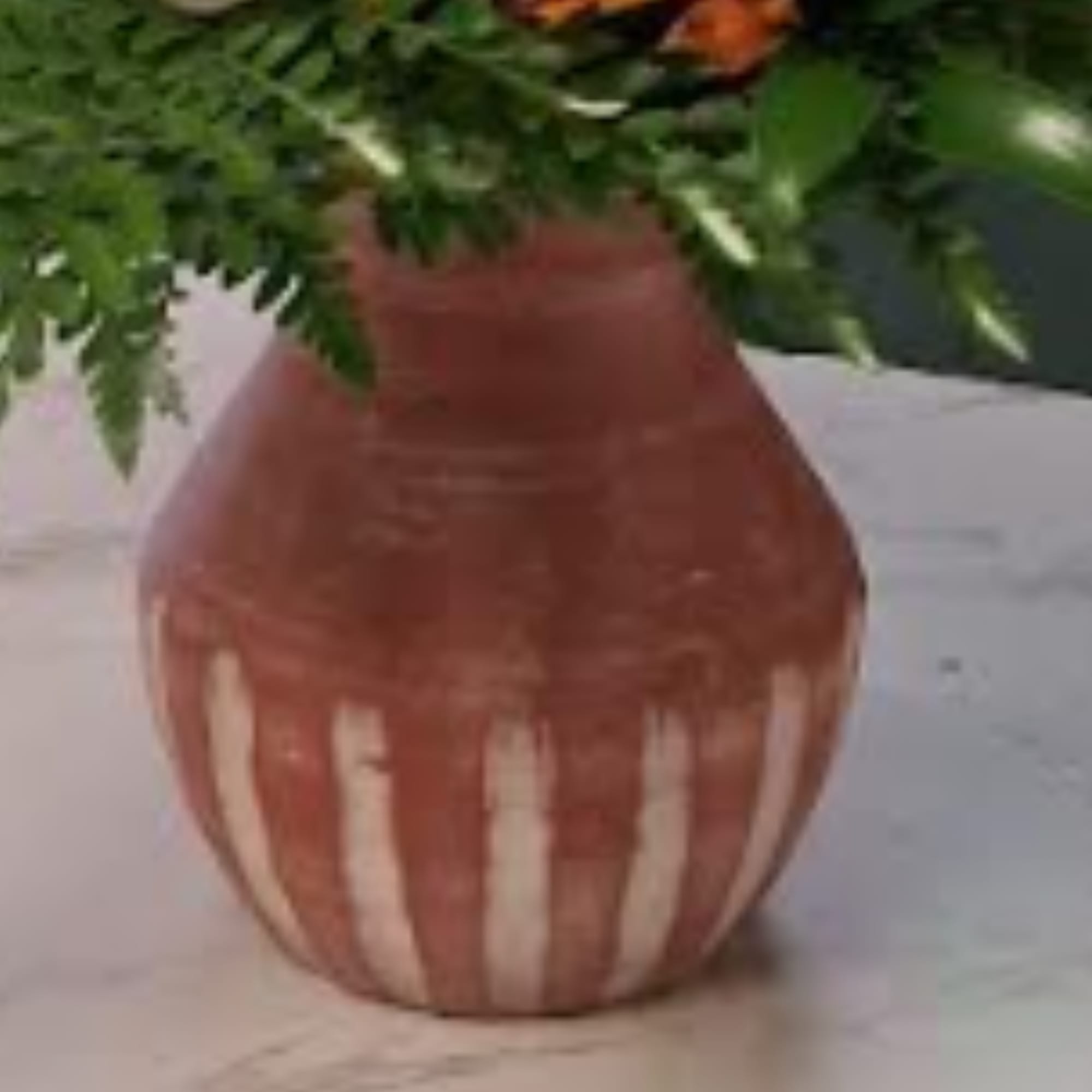 Pink vase holding a floral arrangement with greenery