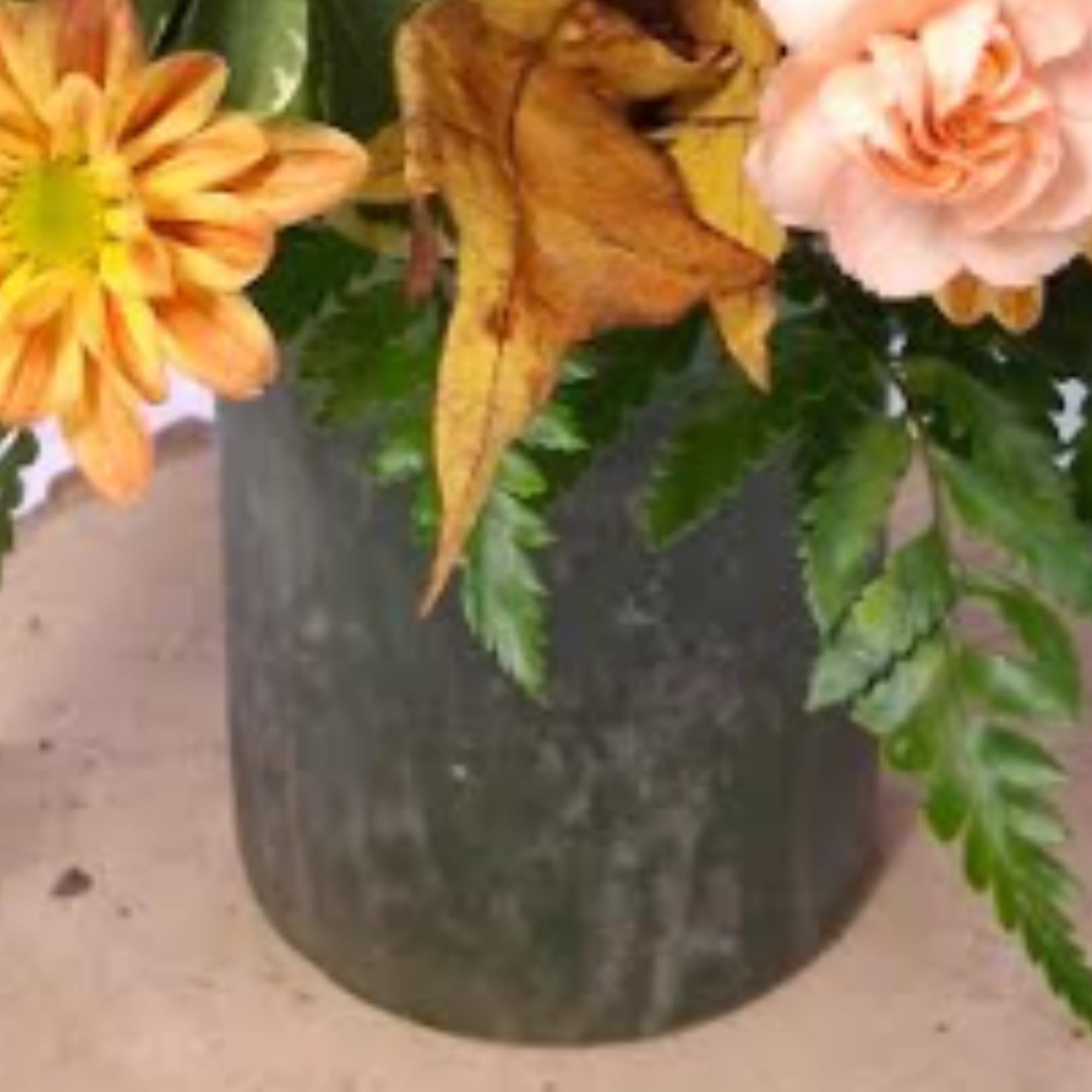 Orange and blush flowers in a dark vase