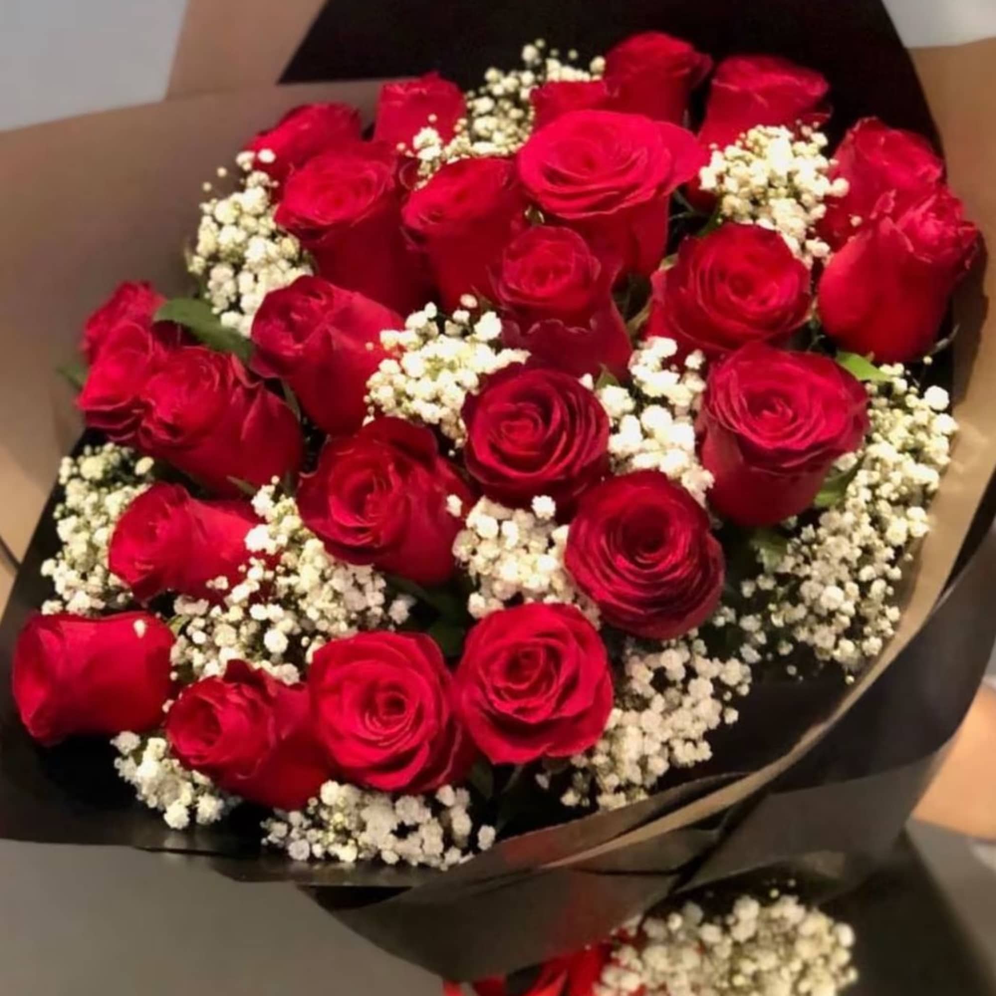 Bouquet of red roses with white baby's breath in black wrapping