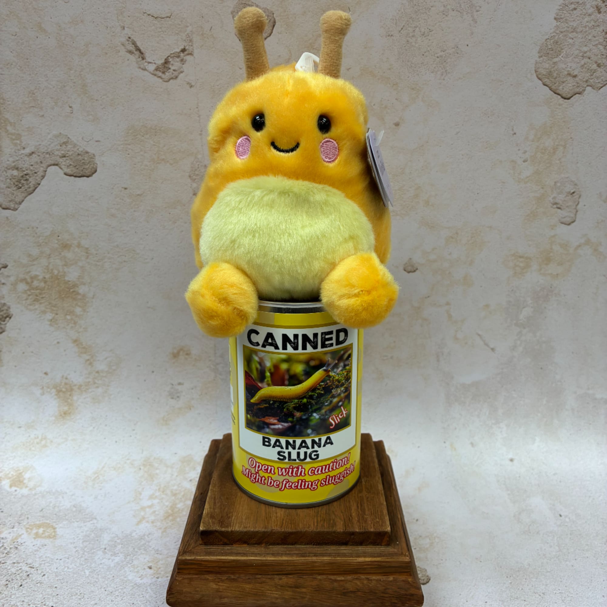 Plush yellow banana slug sitting on a canned display