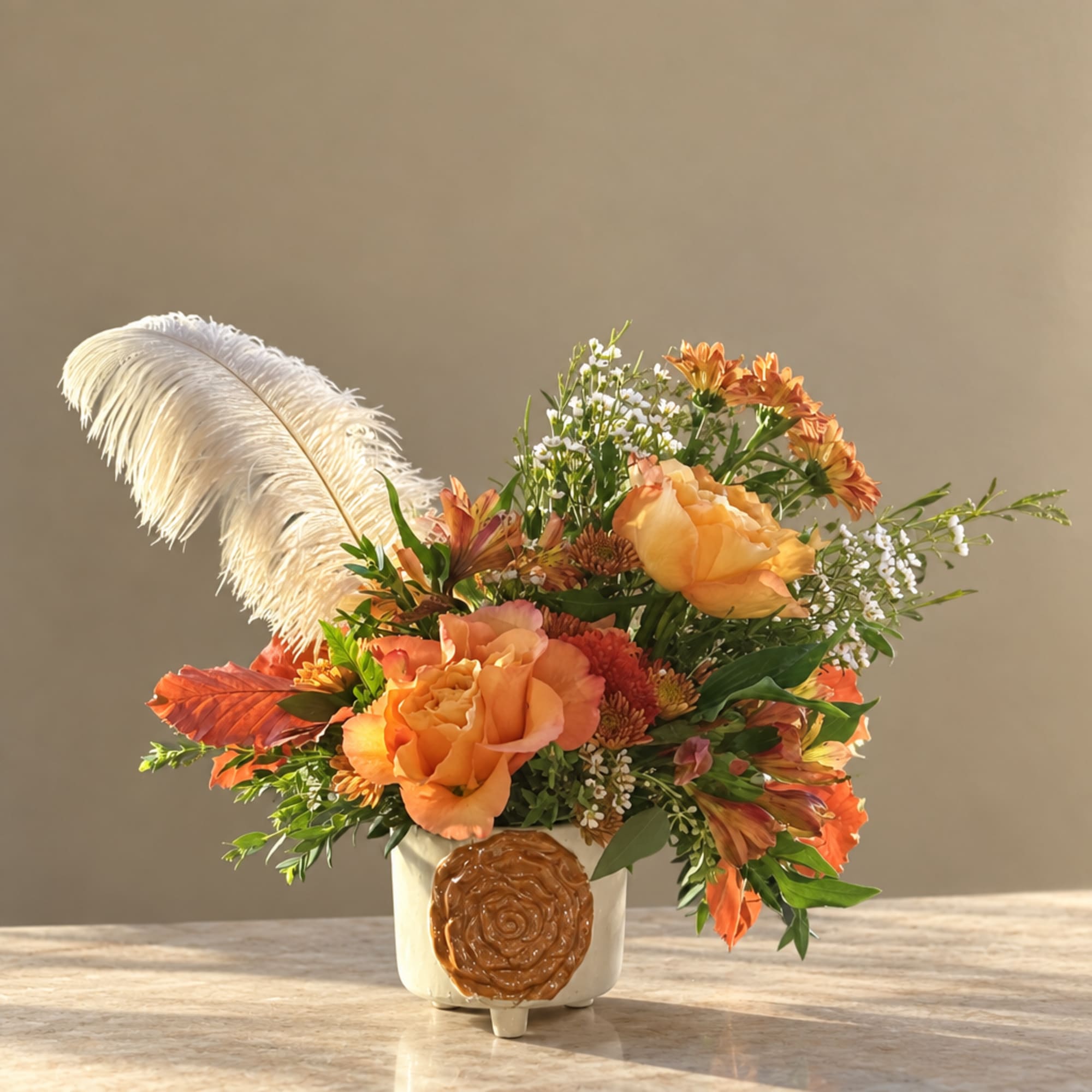 Orange floral arrangement in a white vase with a large white feather