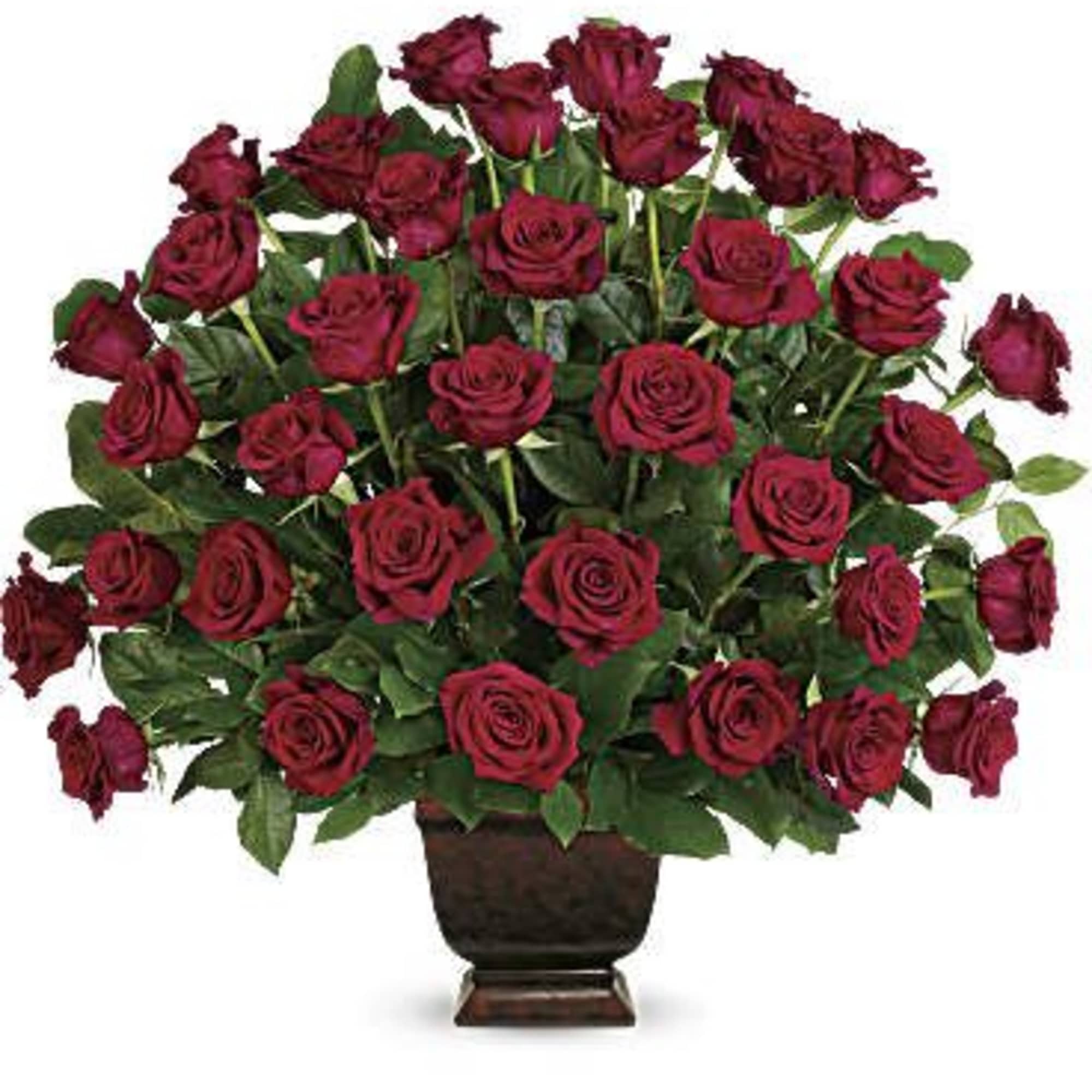 Large arrangement of dark red roses massed in a low brown pedestal vase