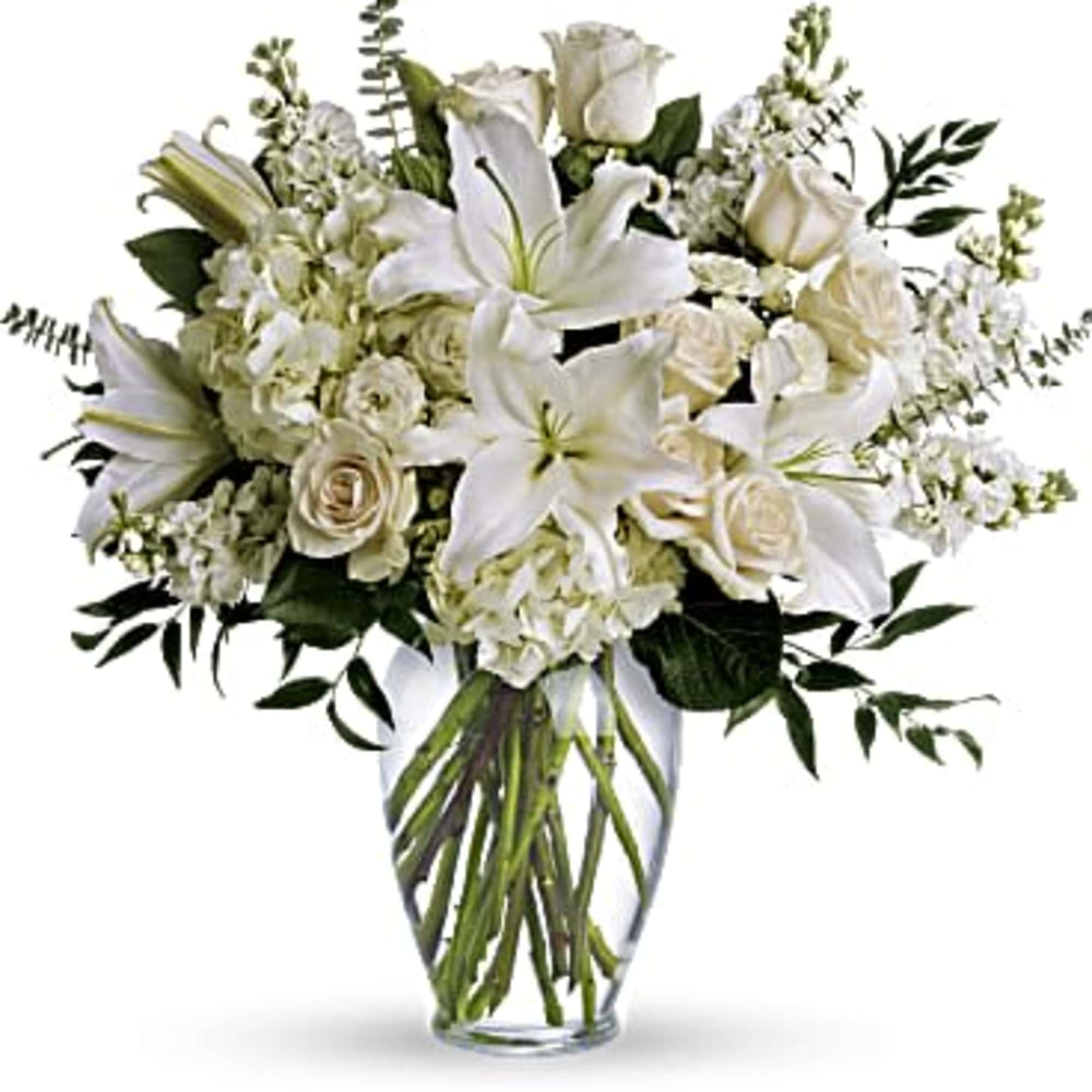 Tall arrangement of white lilies, roses, and hydrangeas in a clear glass vase