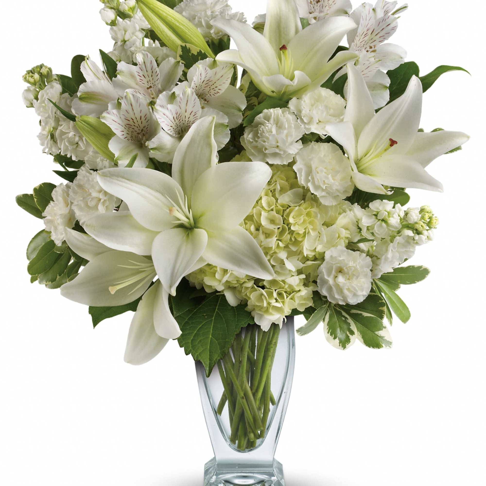 Tall arrangement of white lilies, carnations, hydrangeas and other white flowers in a clear glass vase