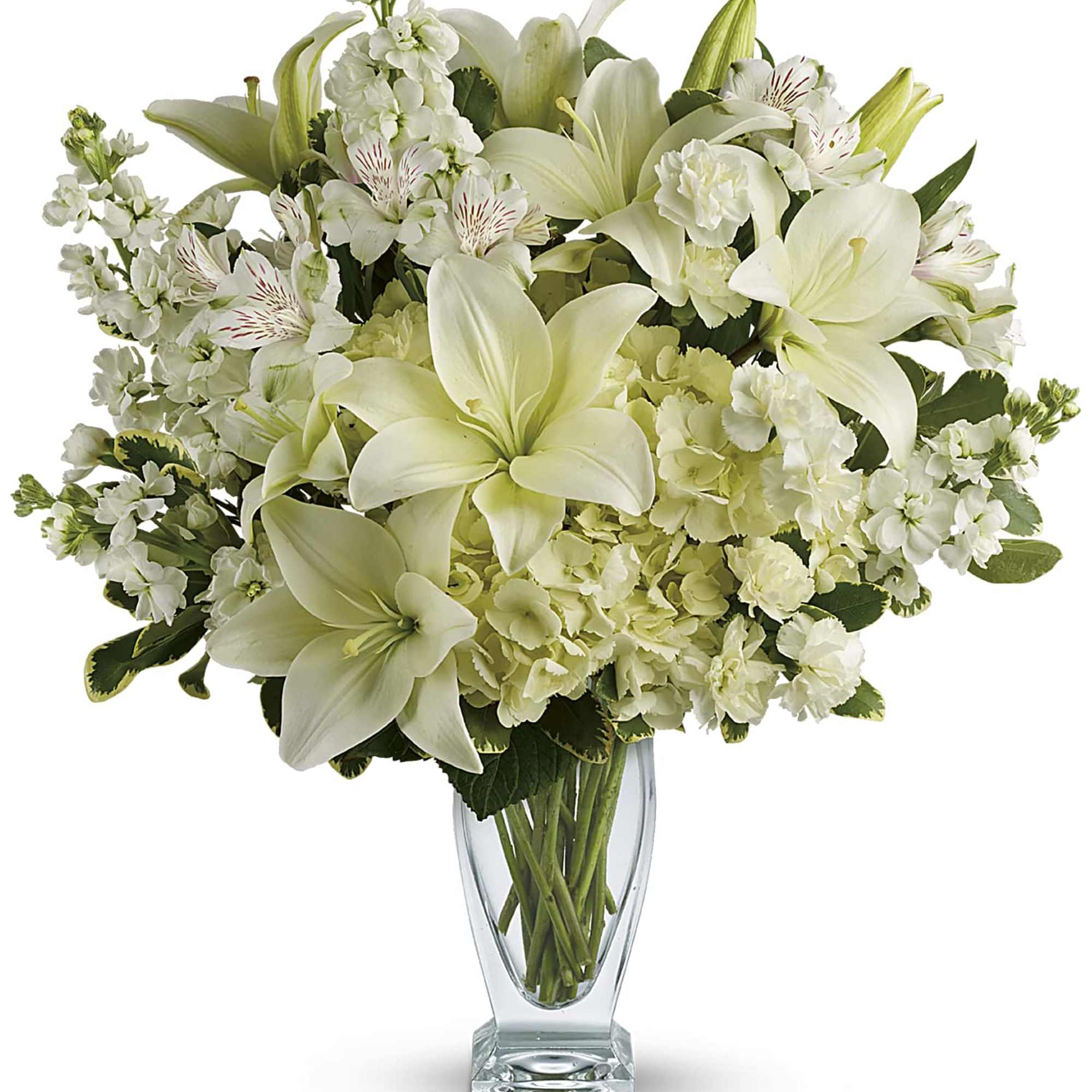 Tall arrangement of white lilies, hydrangeas, carnations and other white blooms in a clear glass vase