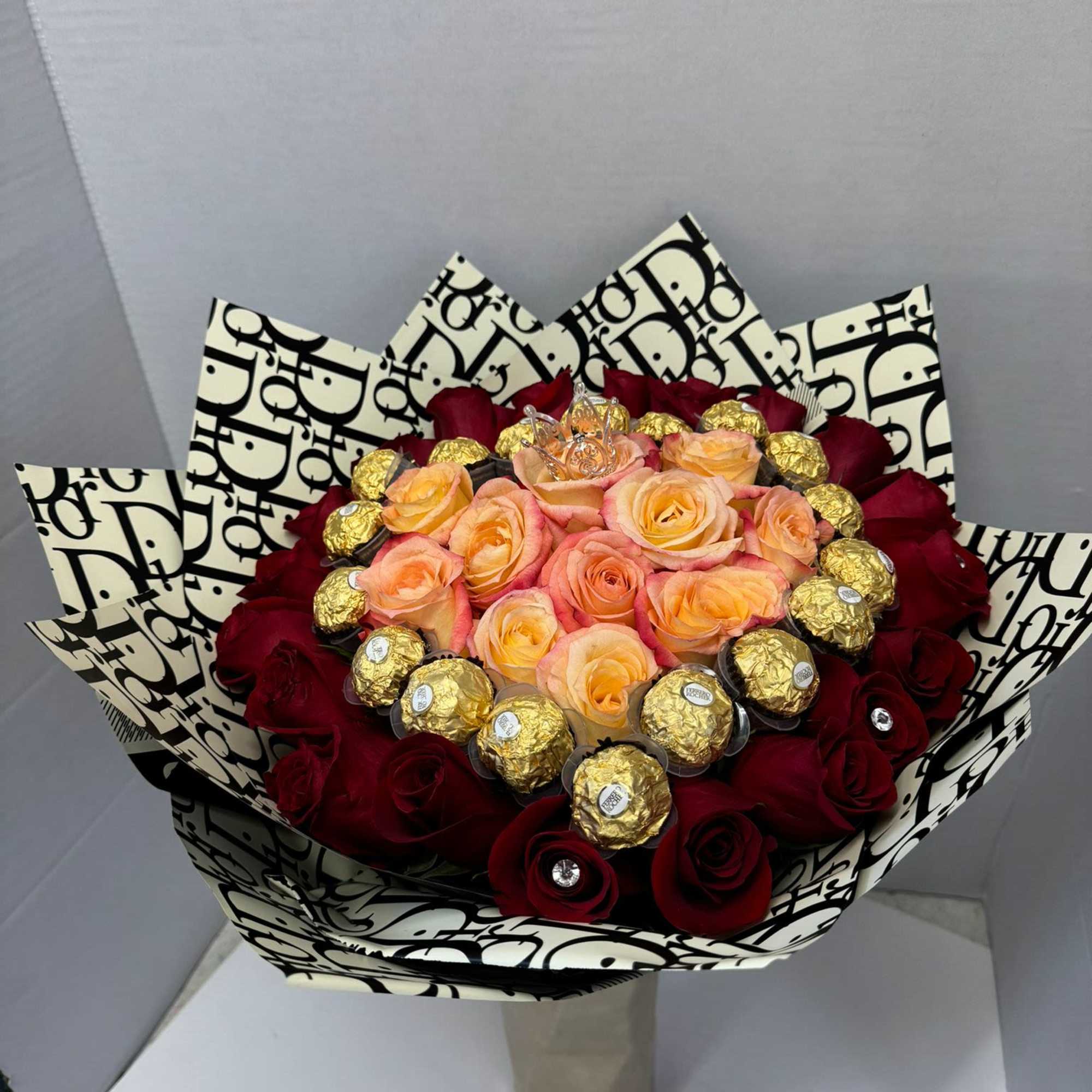 Bouquet of red and peach roses with gold-wrapped chocolates in patterned wrap