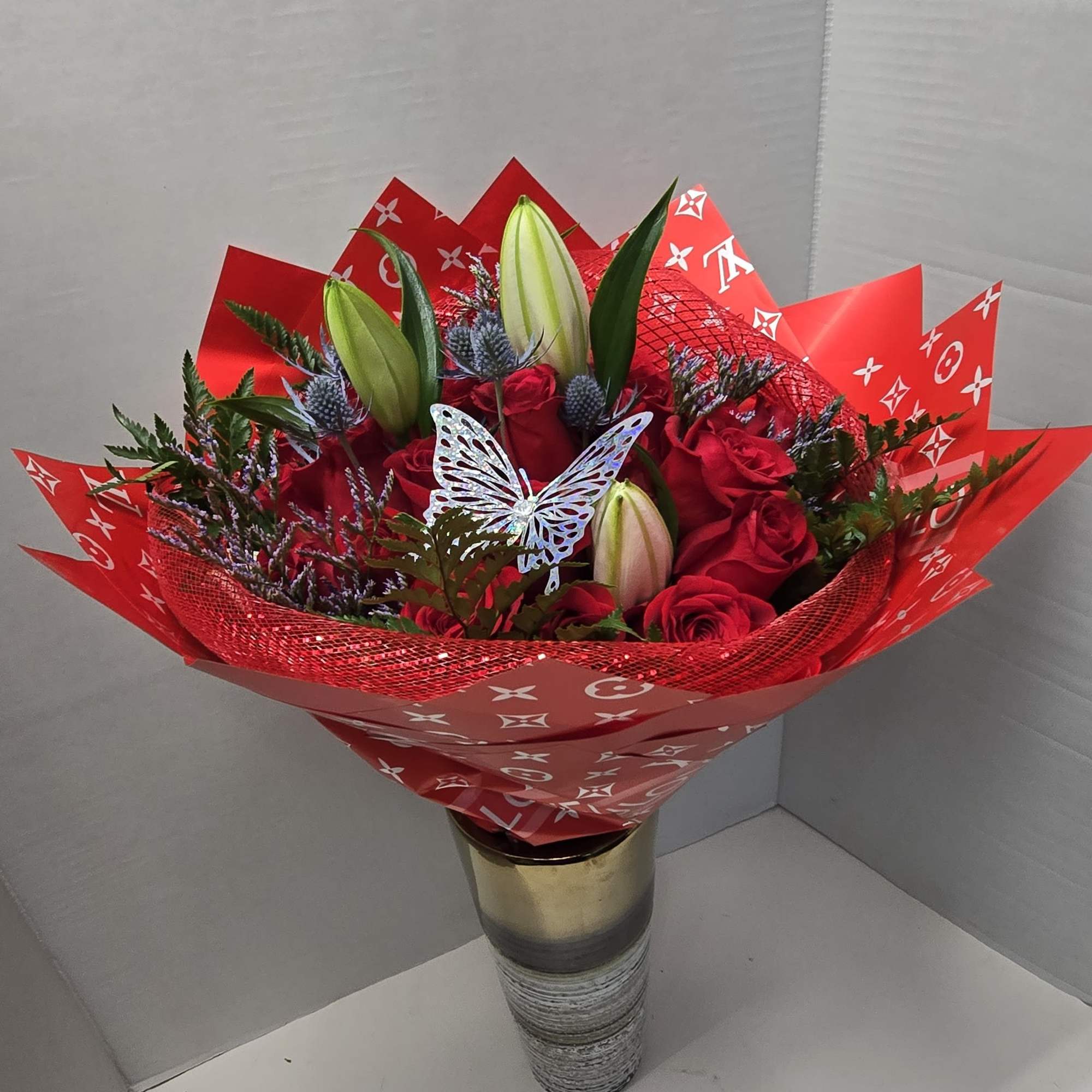 Red rose bouquet with lily buds in a gold vase