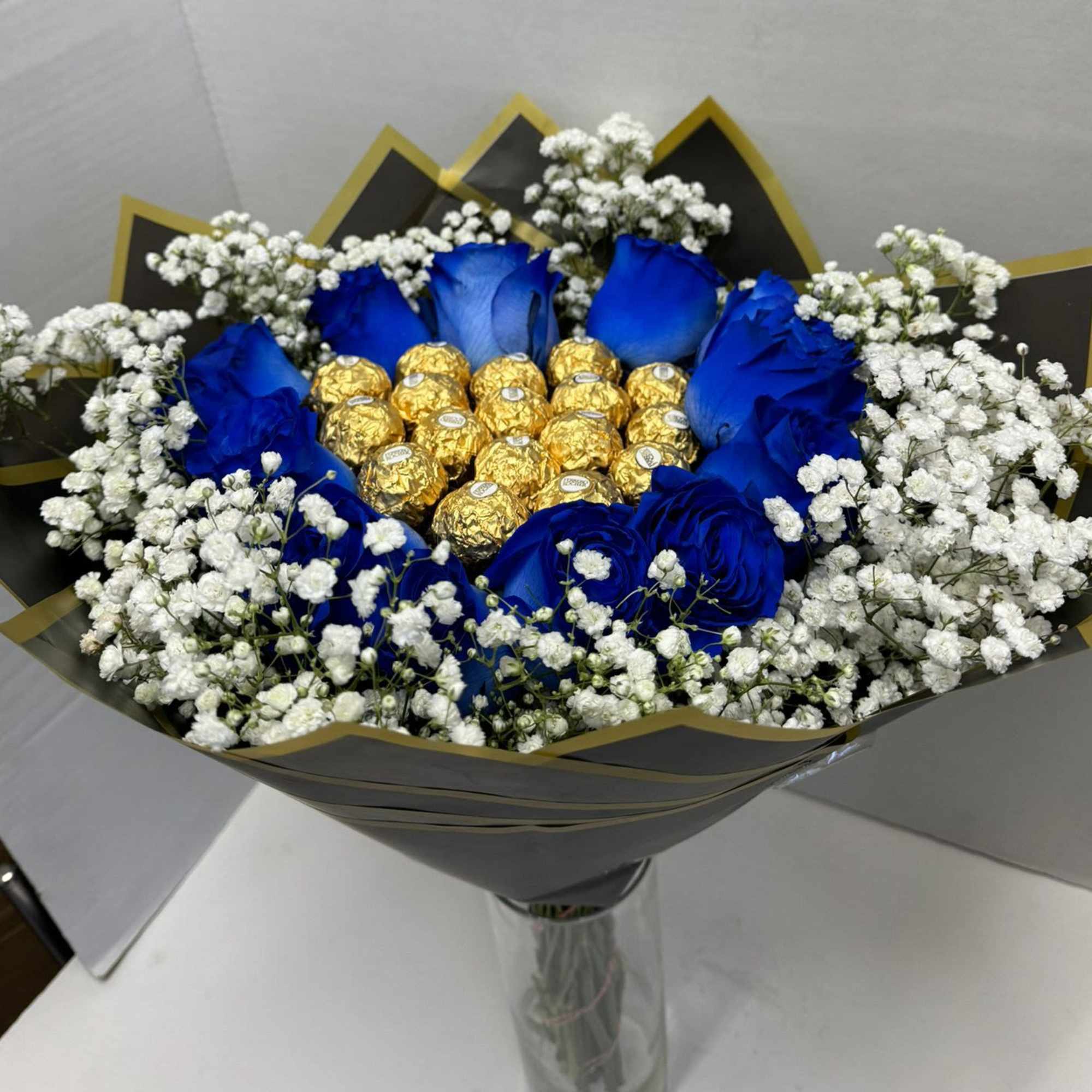 Bouquet of blue roses with gold-wrapped chocolates and white baby's breath
