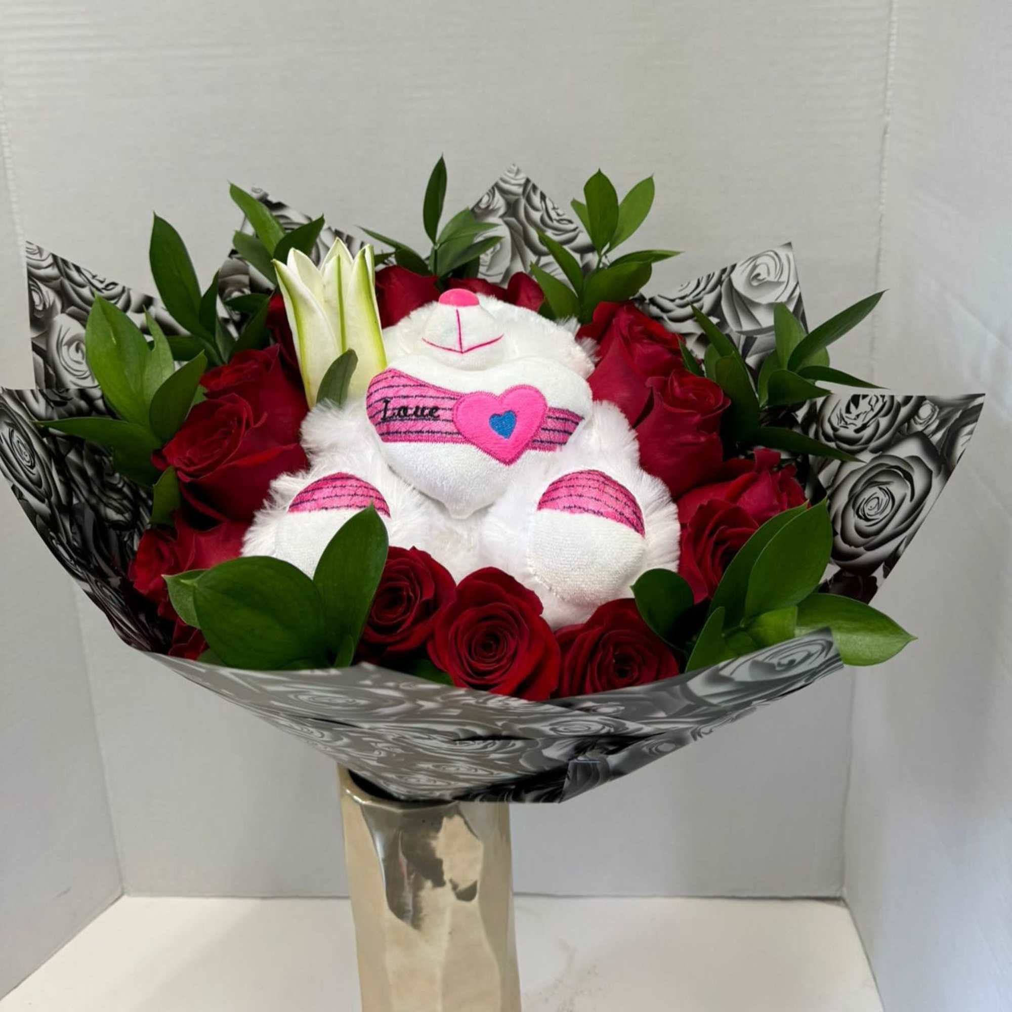 Bouquet of red roses with a white teddy bear in decorative wrap