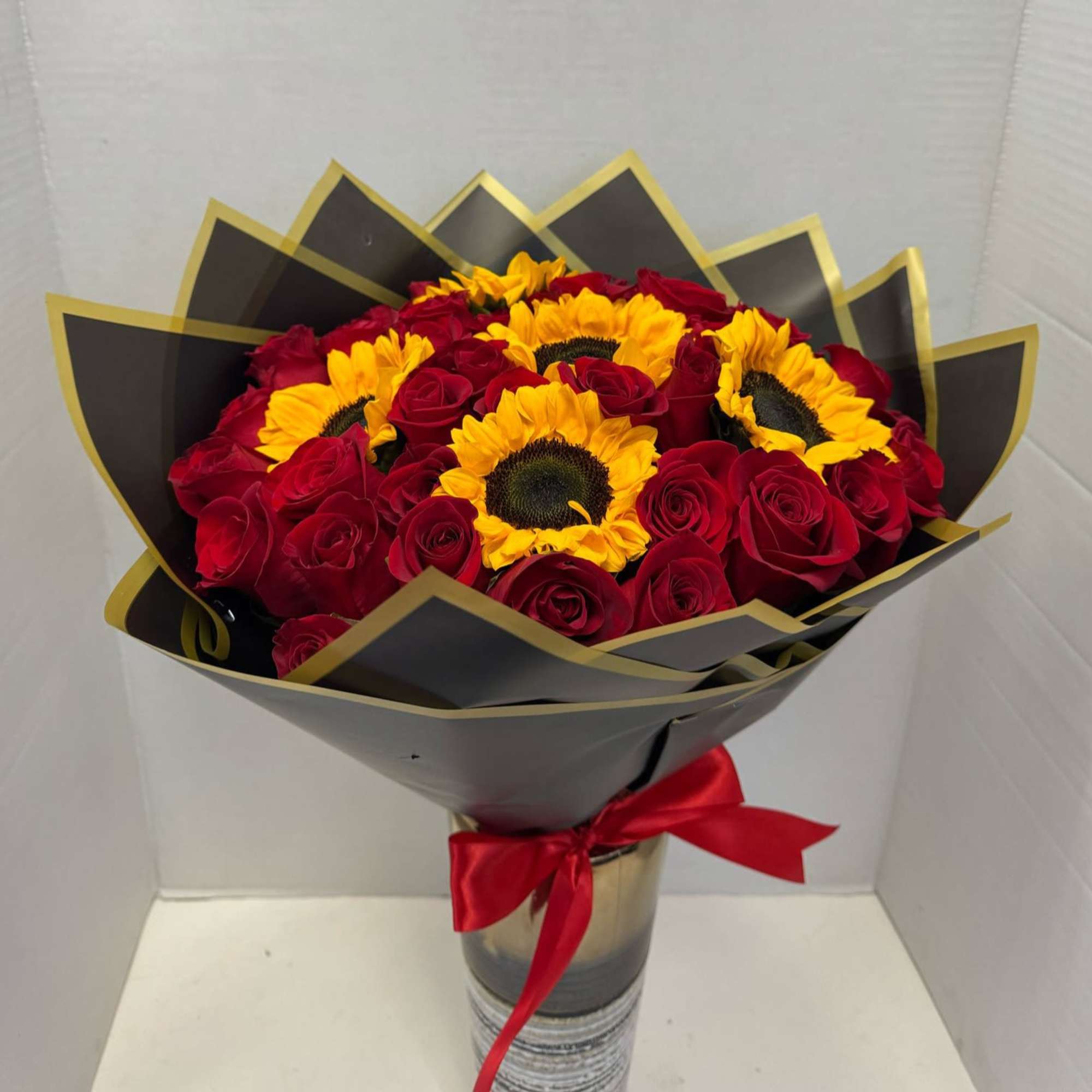 Bouquet of red roses and yellow sunflowers wrapped in black paper
