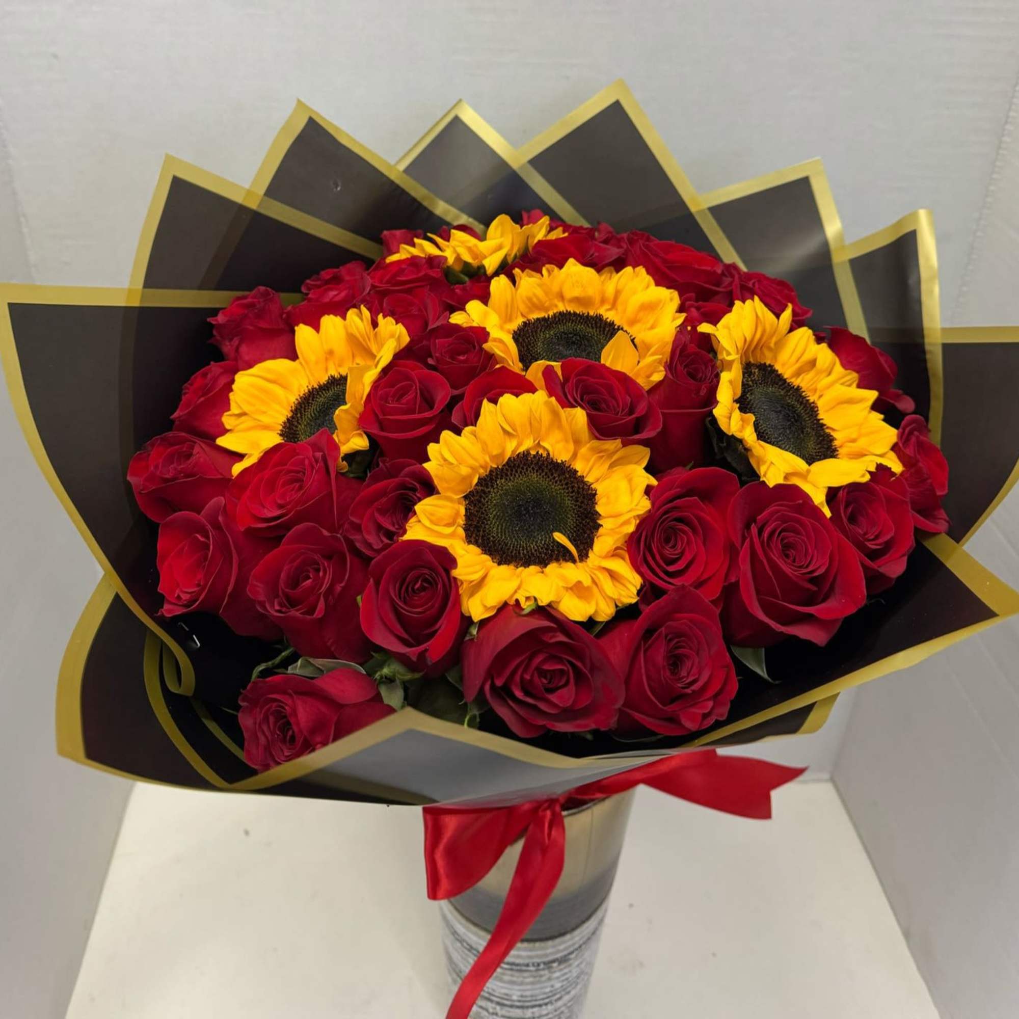 Bouquet of red roses and yellow sunflowers in black and gold wrap