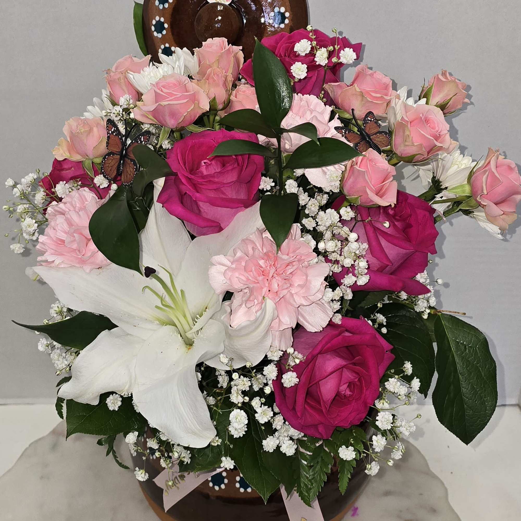 Pink and white rose bouquet with lilies in a brown vase