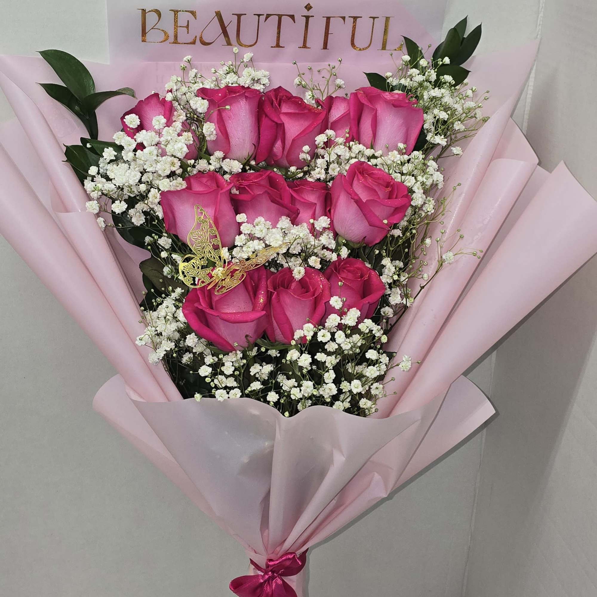 Pink rose bouquet with baby's breath in pink wrapping and a "BEAUTIFUL" card