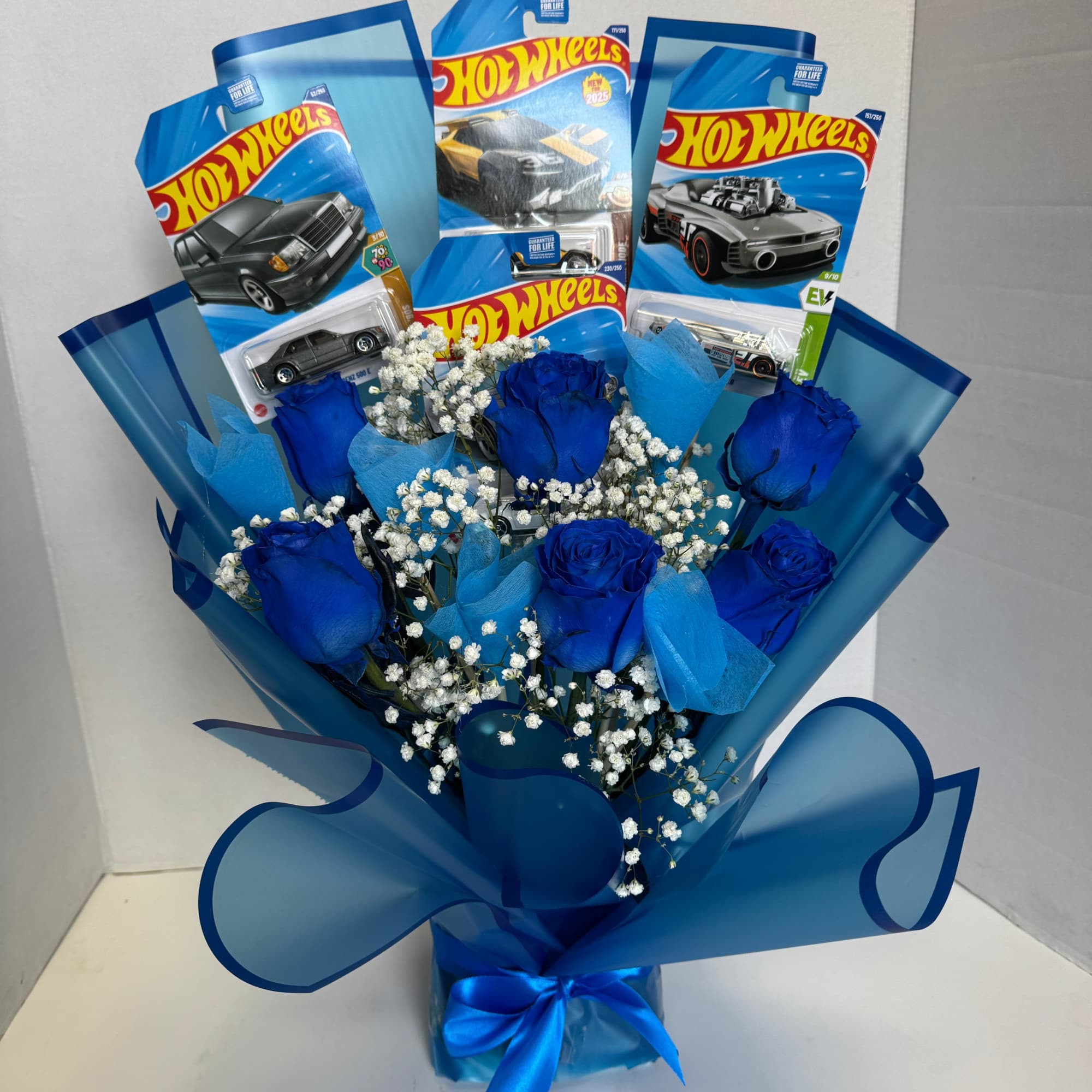 Blue roses and baby’s breath arranged with Hot Wheels toy car packages