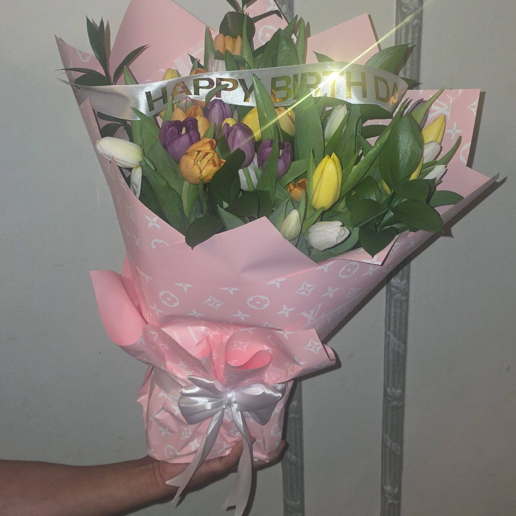 Bouquet of multicolored tulips wrapped in pink paper with a silver ribbon