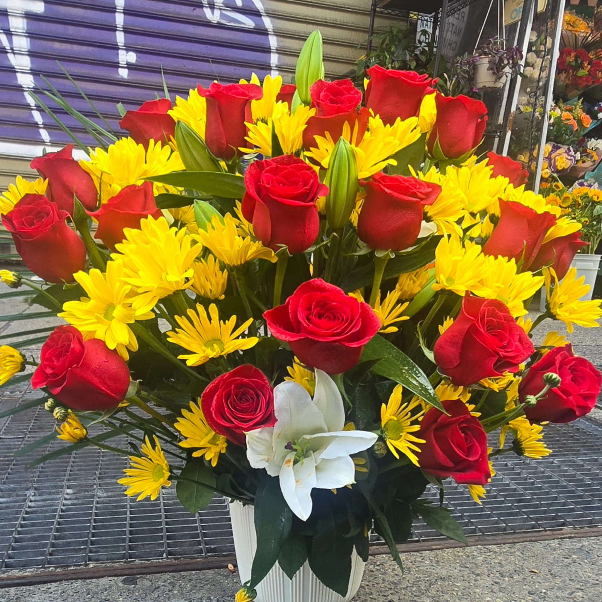 Red roses and yellow daisies in a white vase