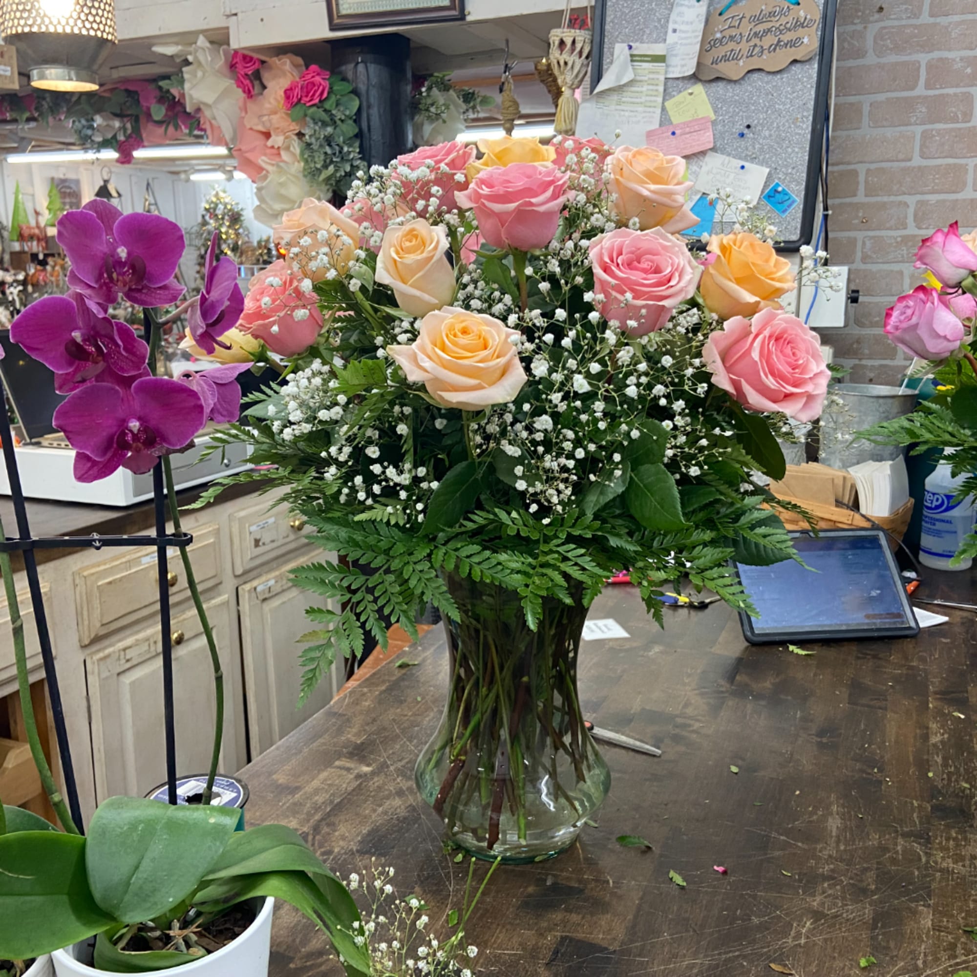 Pink and peach roses arranged in a glass vase with baby's breath
