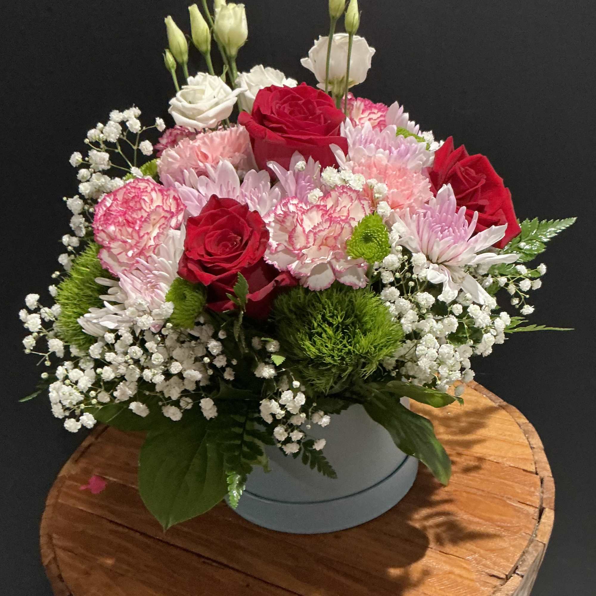 Bouquet of red and pink roses with white blooms in a round vase