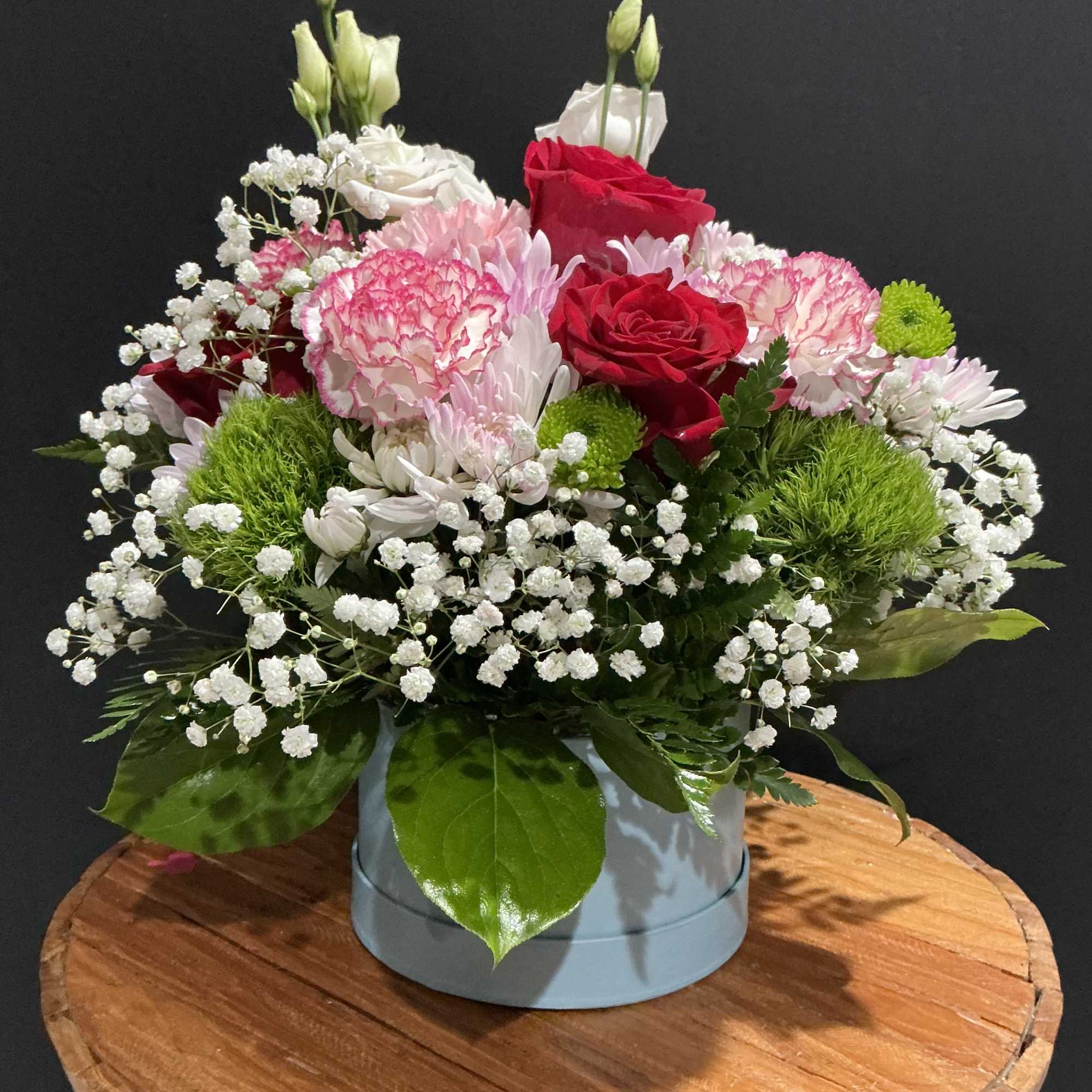 Mixed bouquet of red and pink roses with white filler flowers in a round box