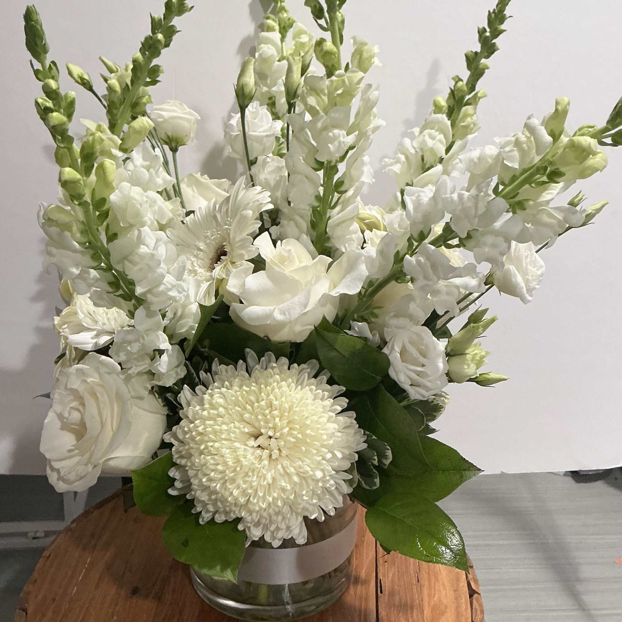 White floral arrangement in a glass vase with tall spikes and round blooms