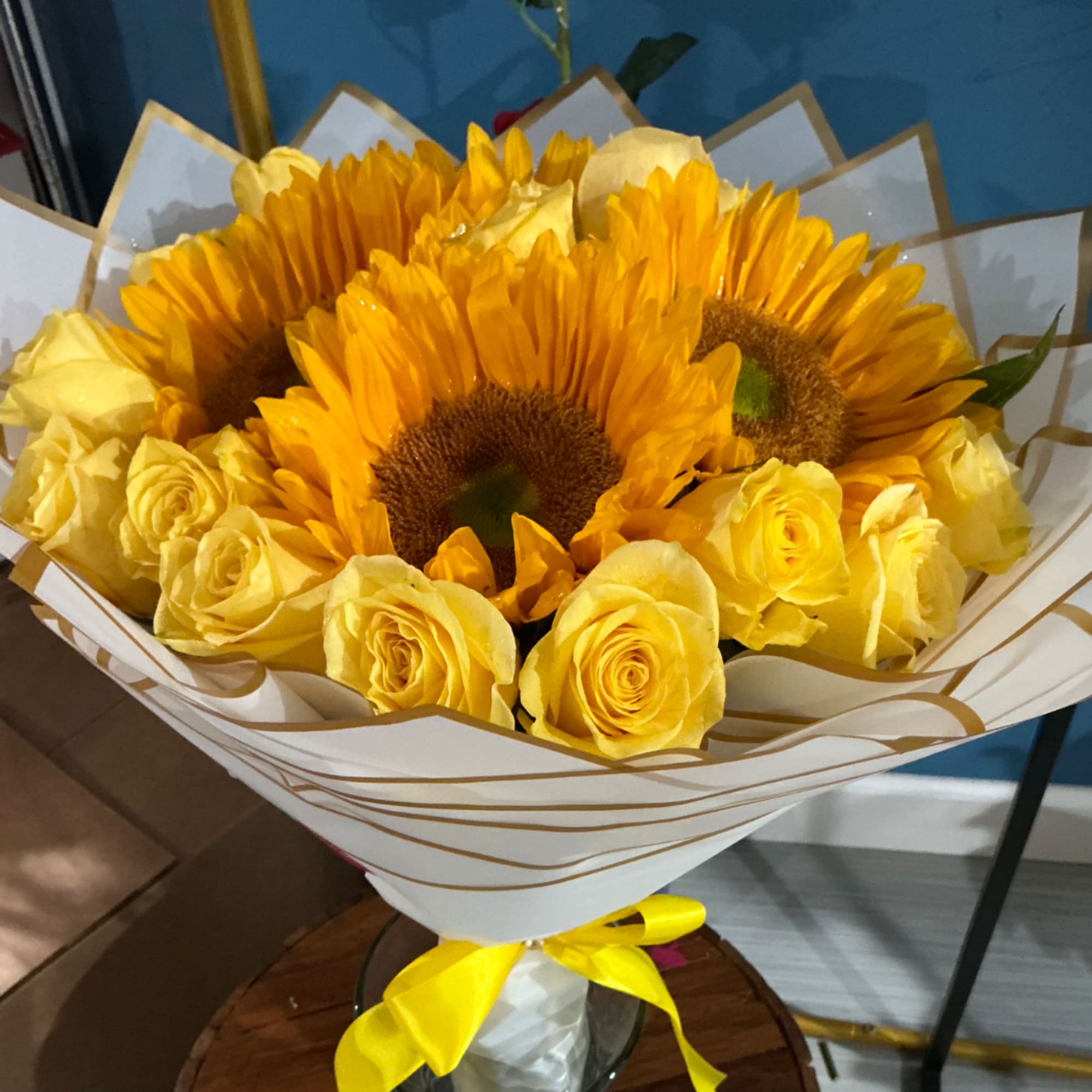 Bouquet of yellow sunflowers and roses wrapped in white paper
