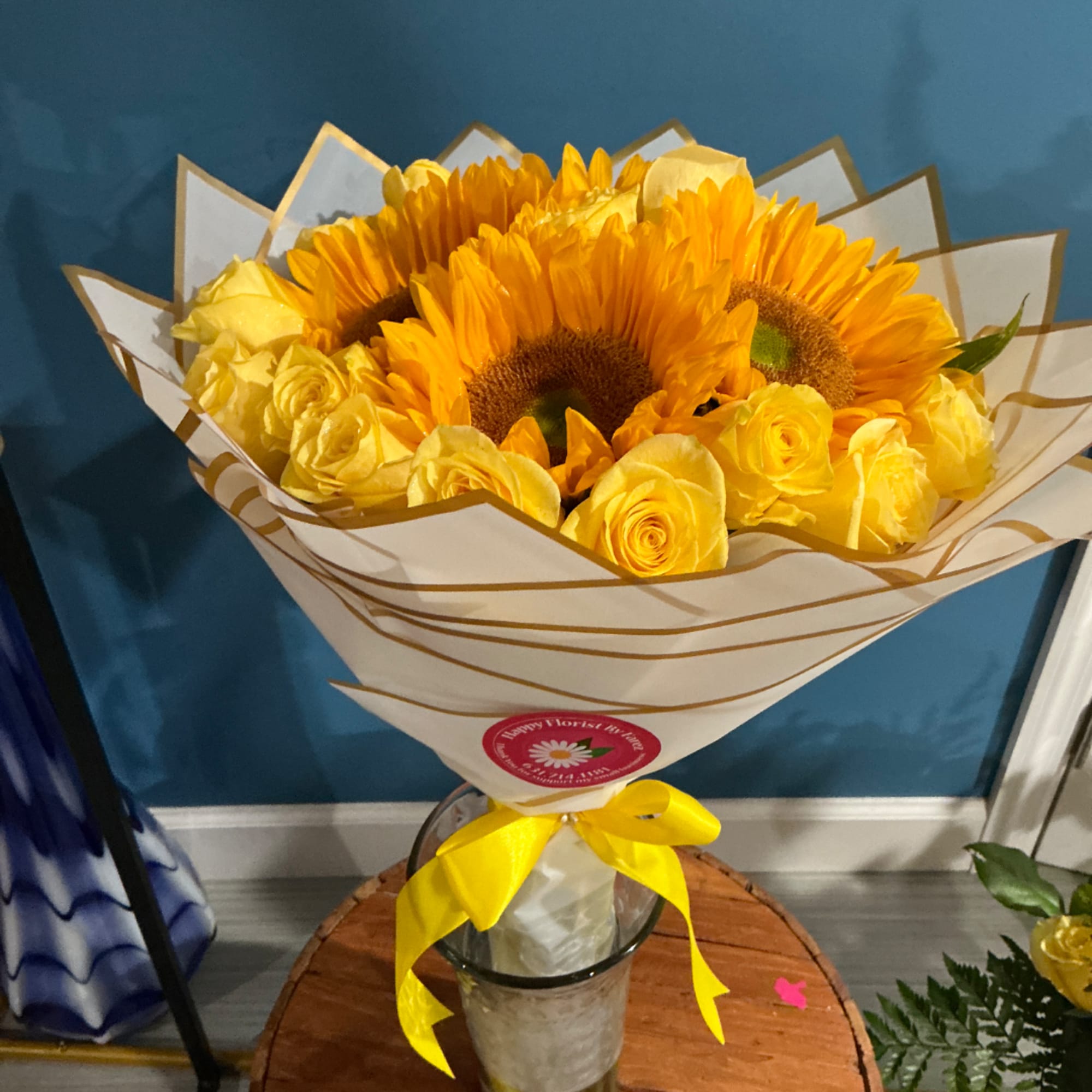 Yellow sunflower and rose bouquet in a clear vase with a yellow ribbon