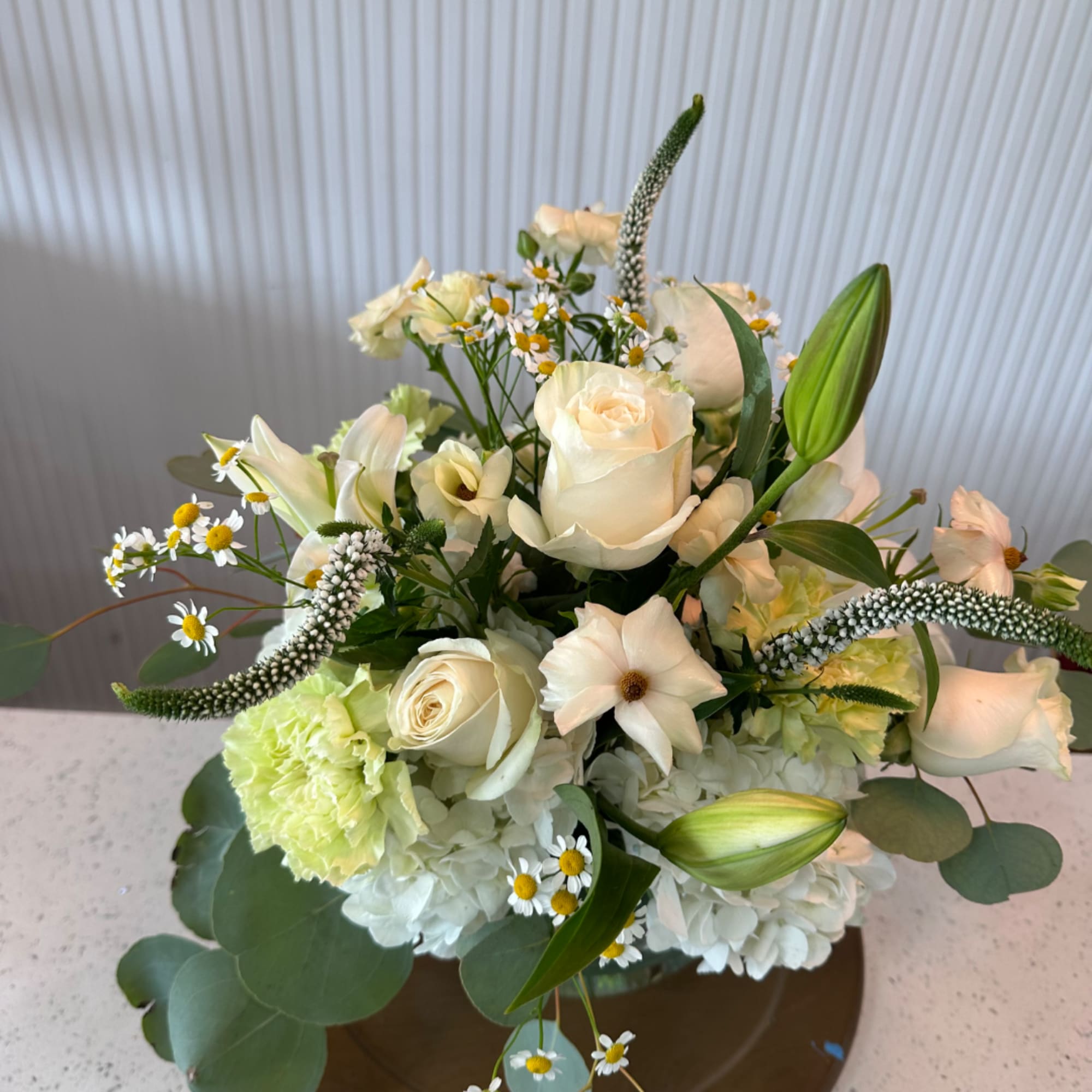 Cream rose and lily bouquet with white hydrangeas in a vase