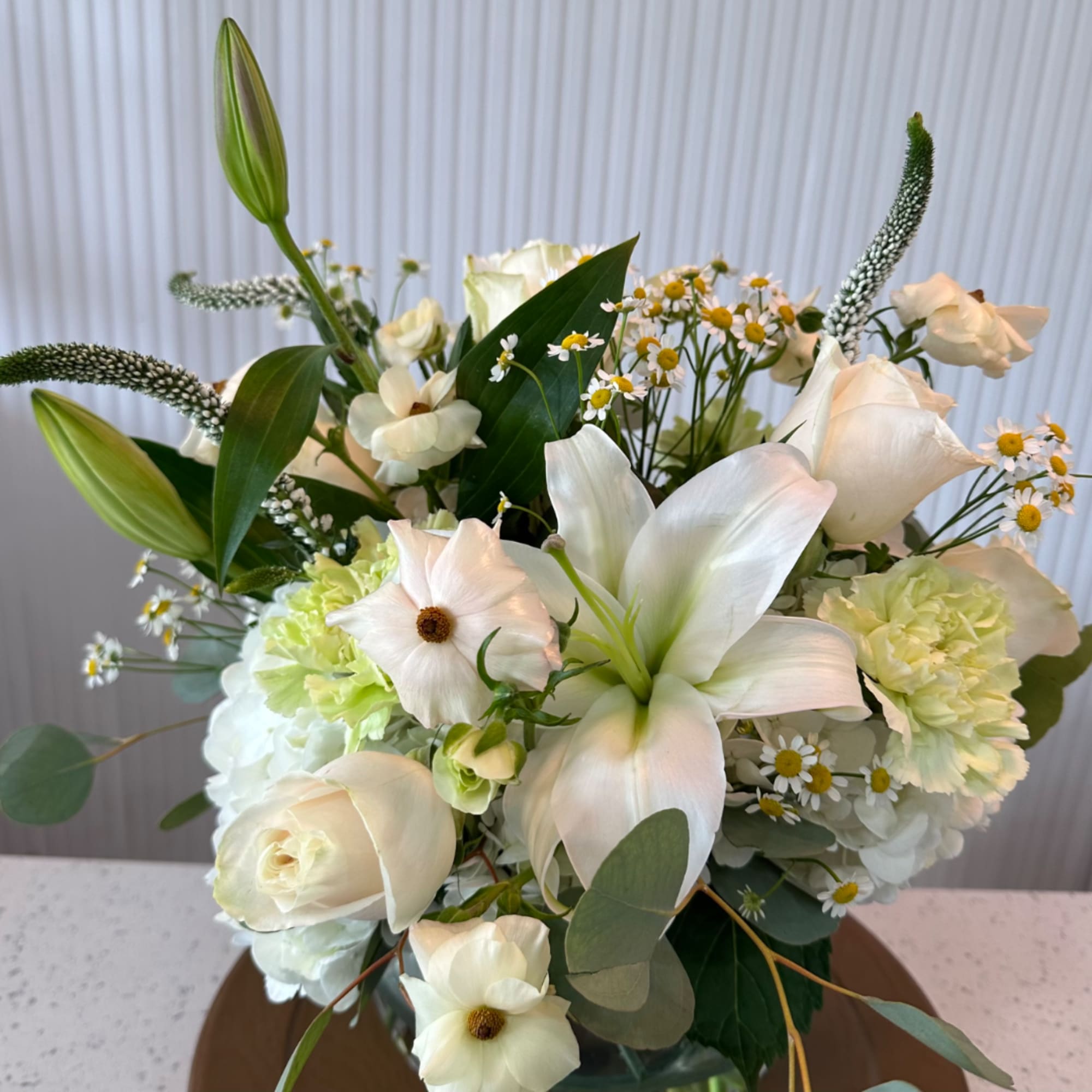 White floral bouquet with lilies, roses, and small daisy-like flowers