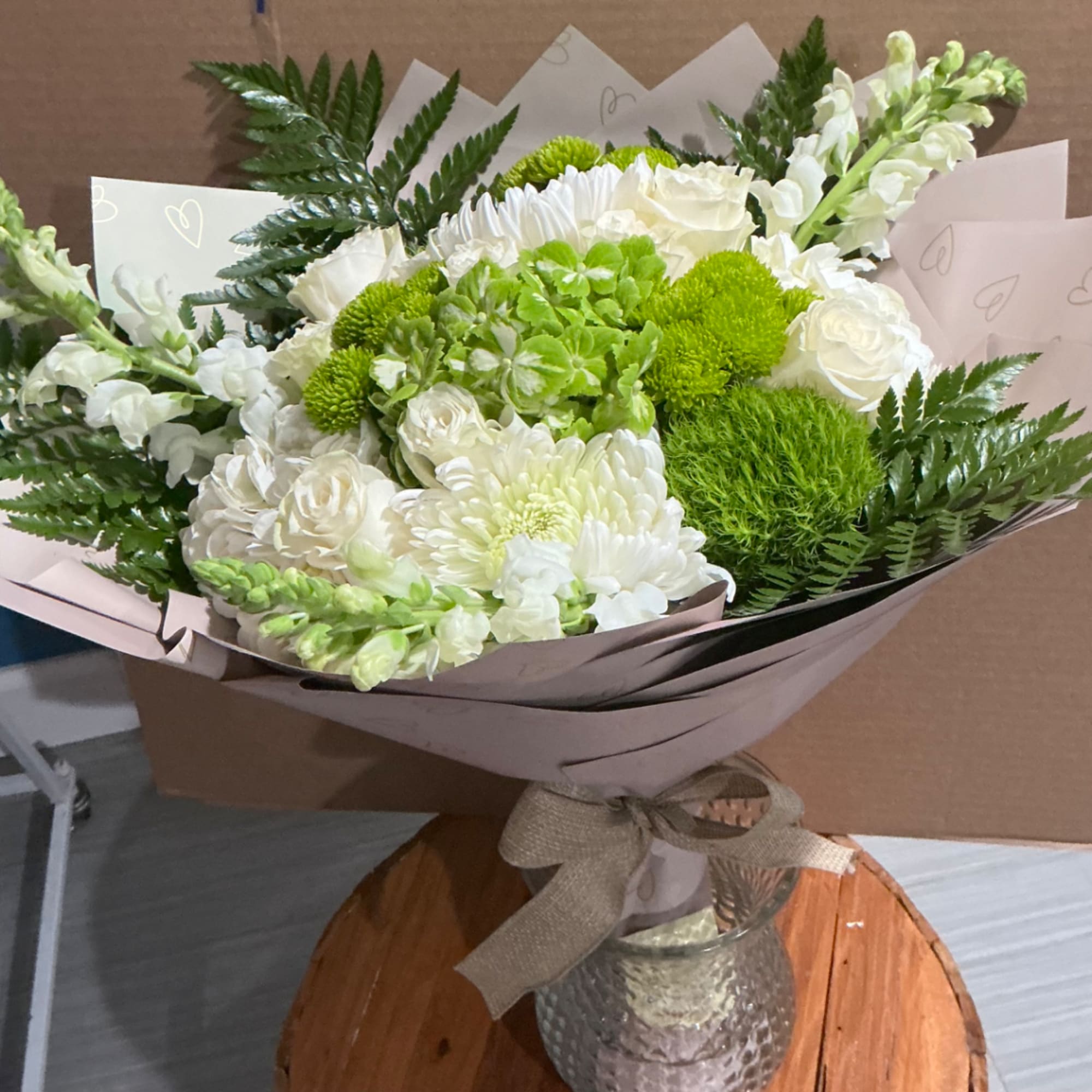 White and green bouquet in a glass vase with a ribbon