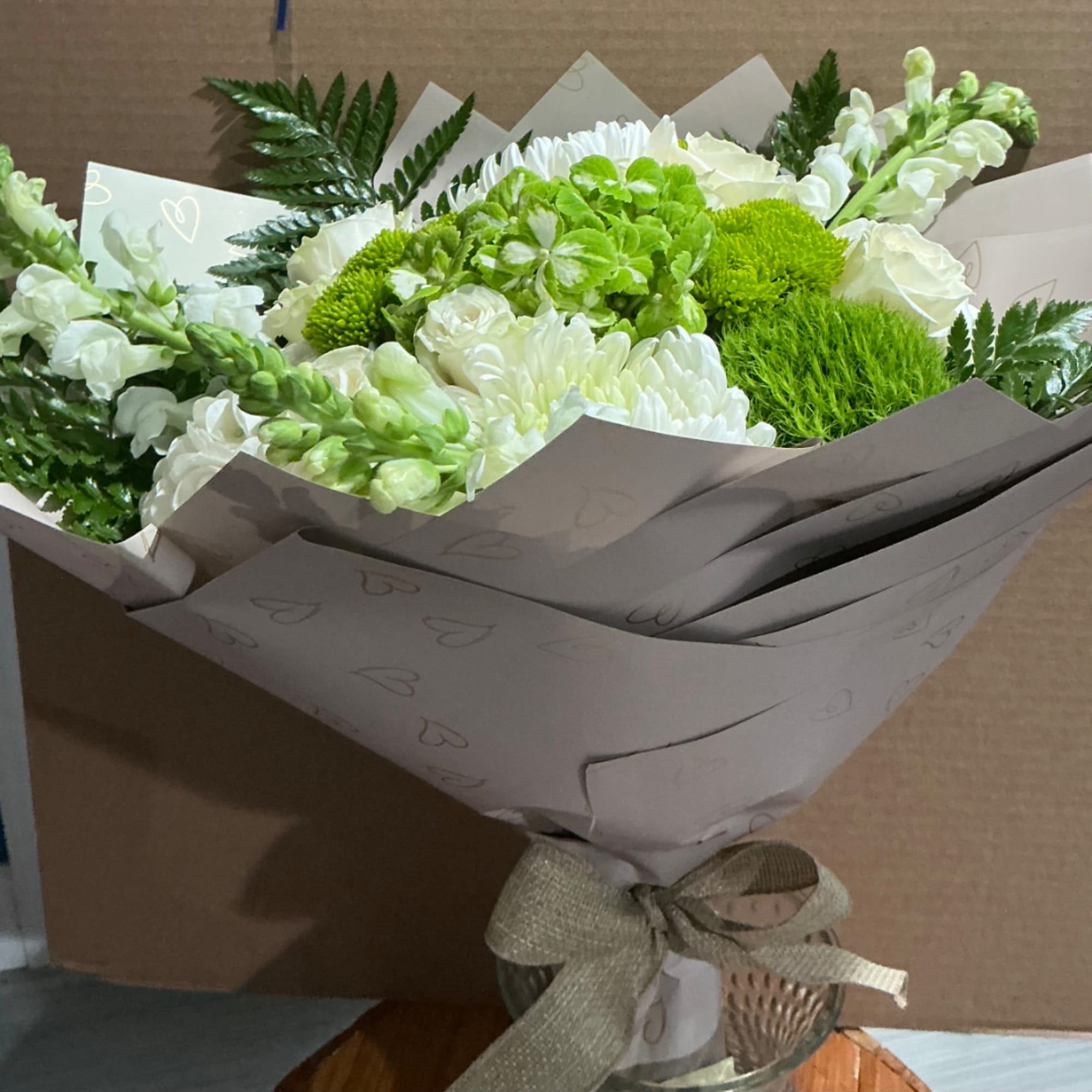Bouquet of white and green flowers wrapped in paper with a ribbon