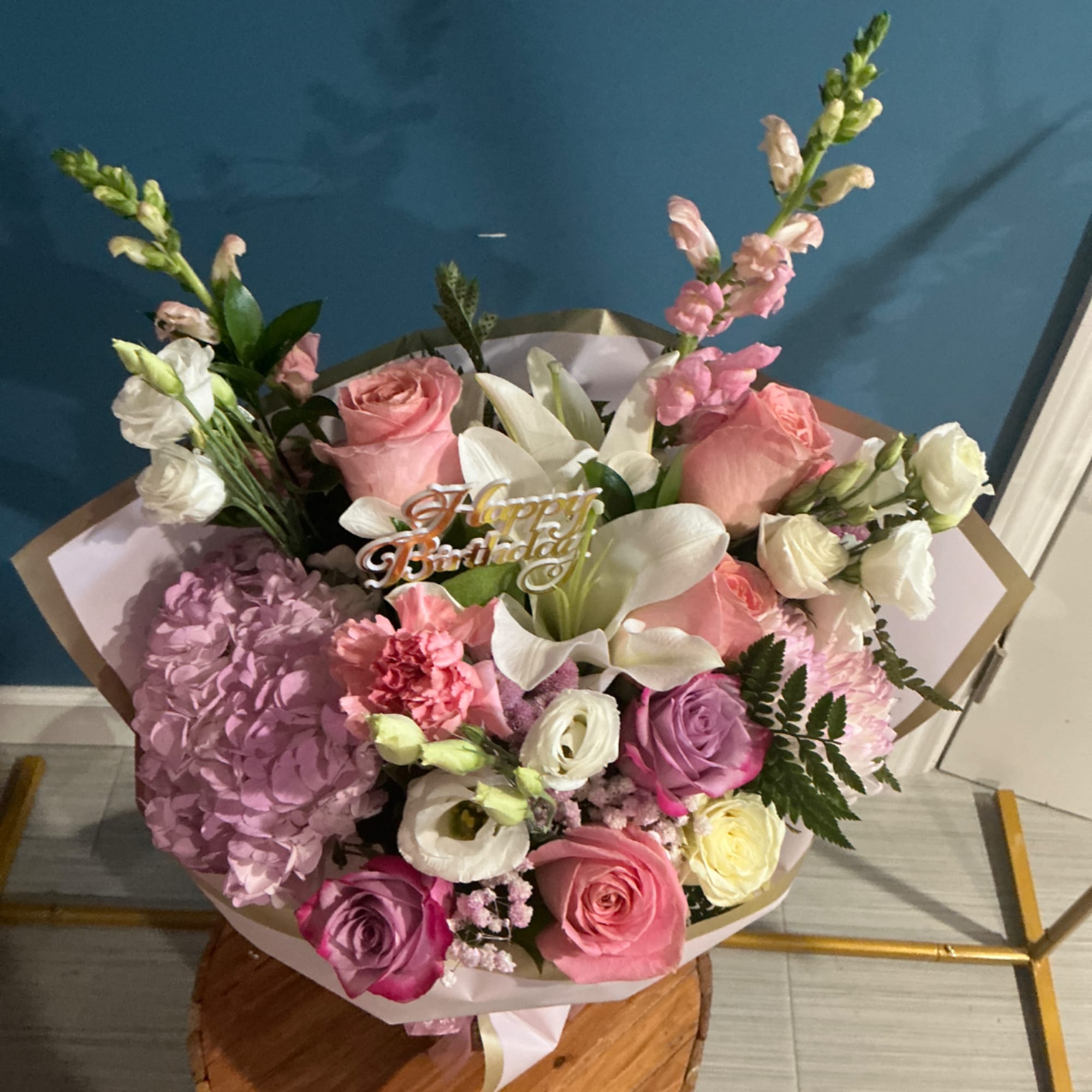 Bouquet of pink, white, and purple flowers with a birthday topper
