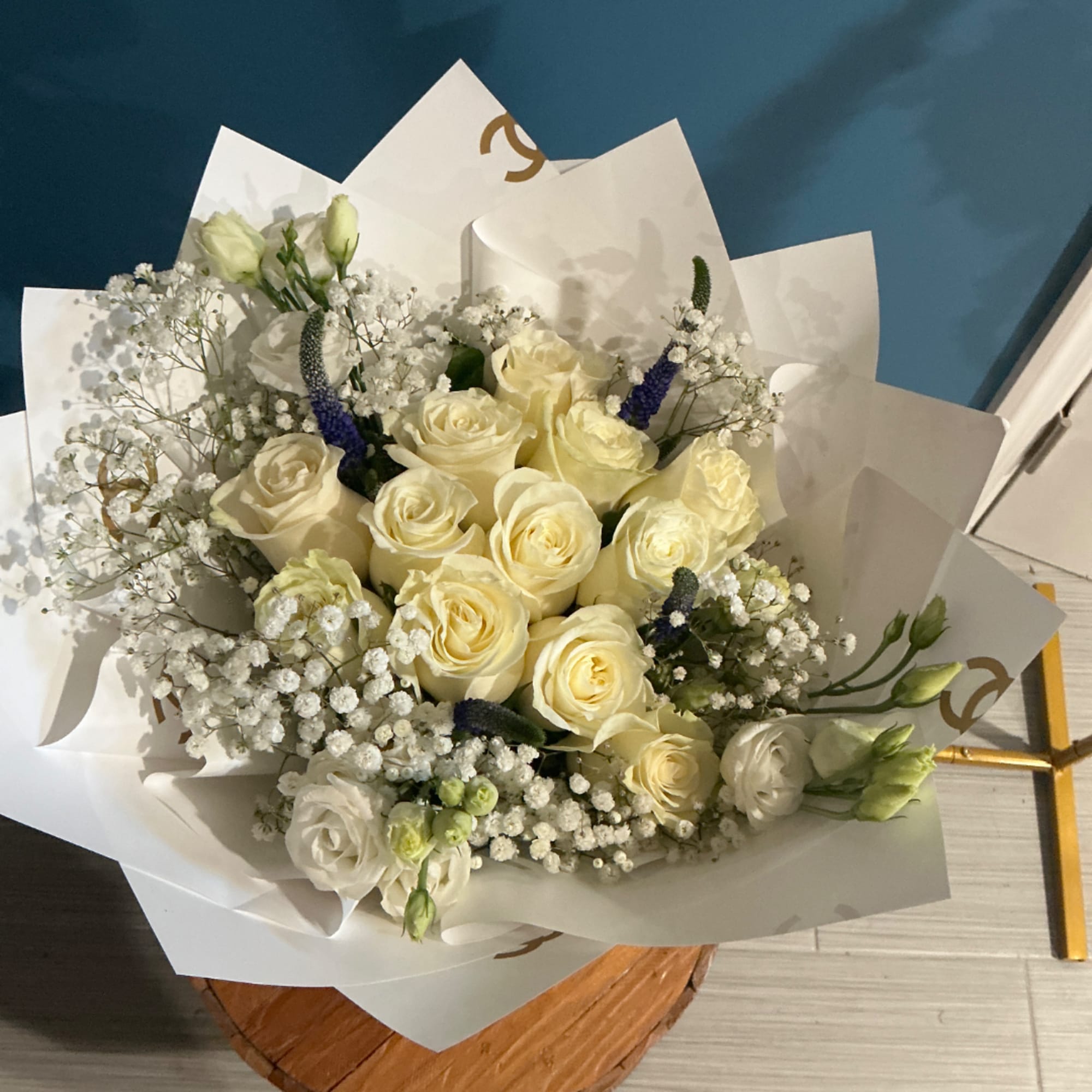 Bouquet of cream roses and white filler flowers wrapped in white paper