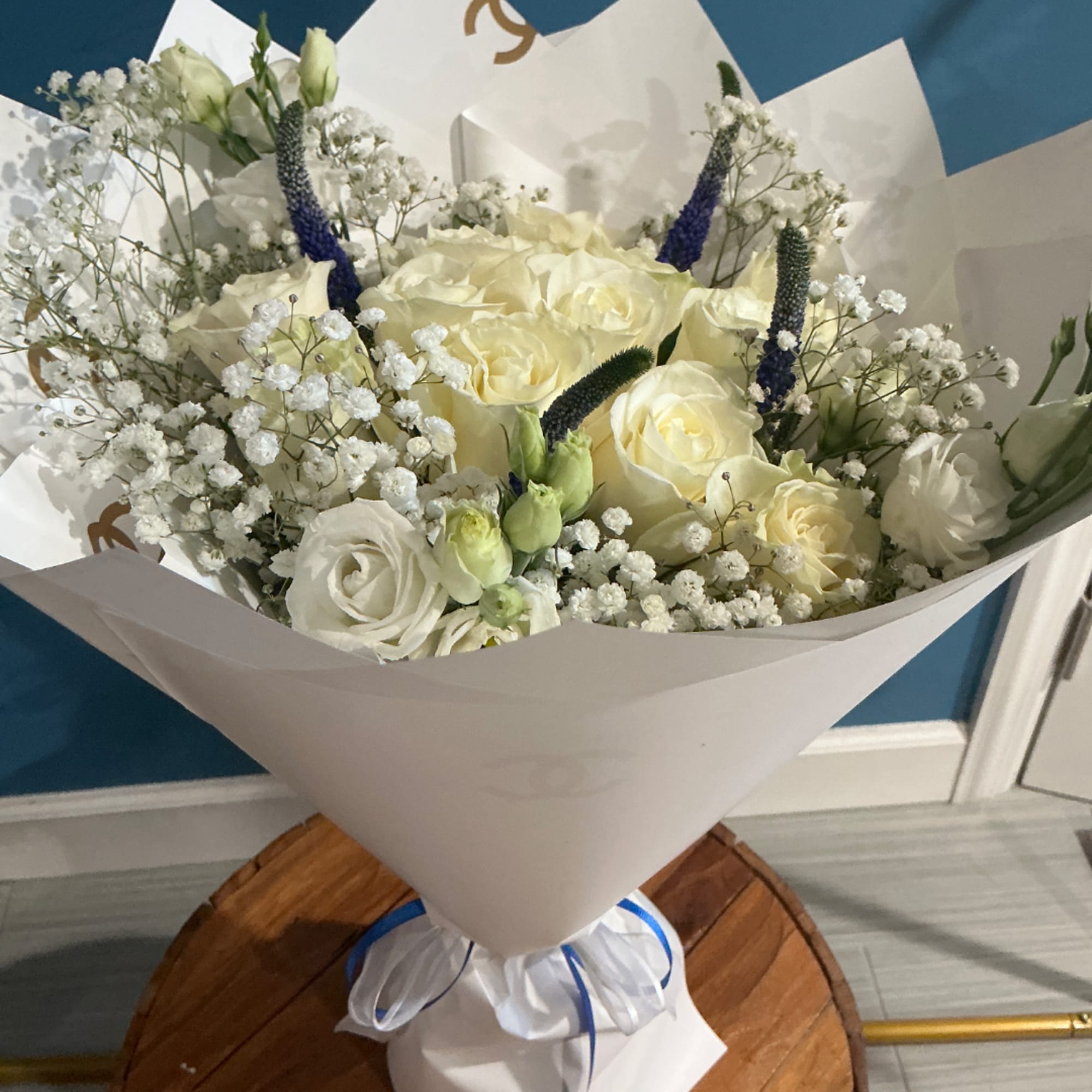 Bouquet of white roses and baby's breath with blue accents in white wrap